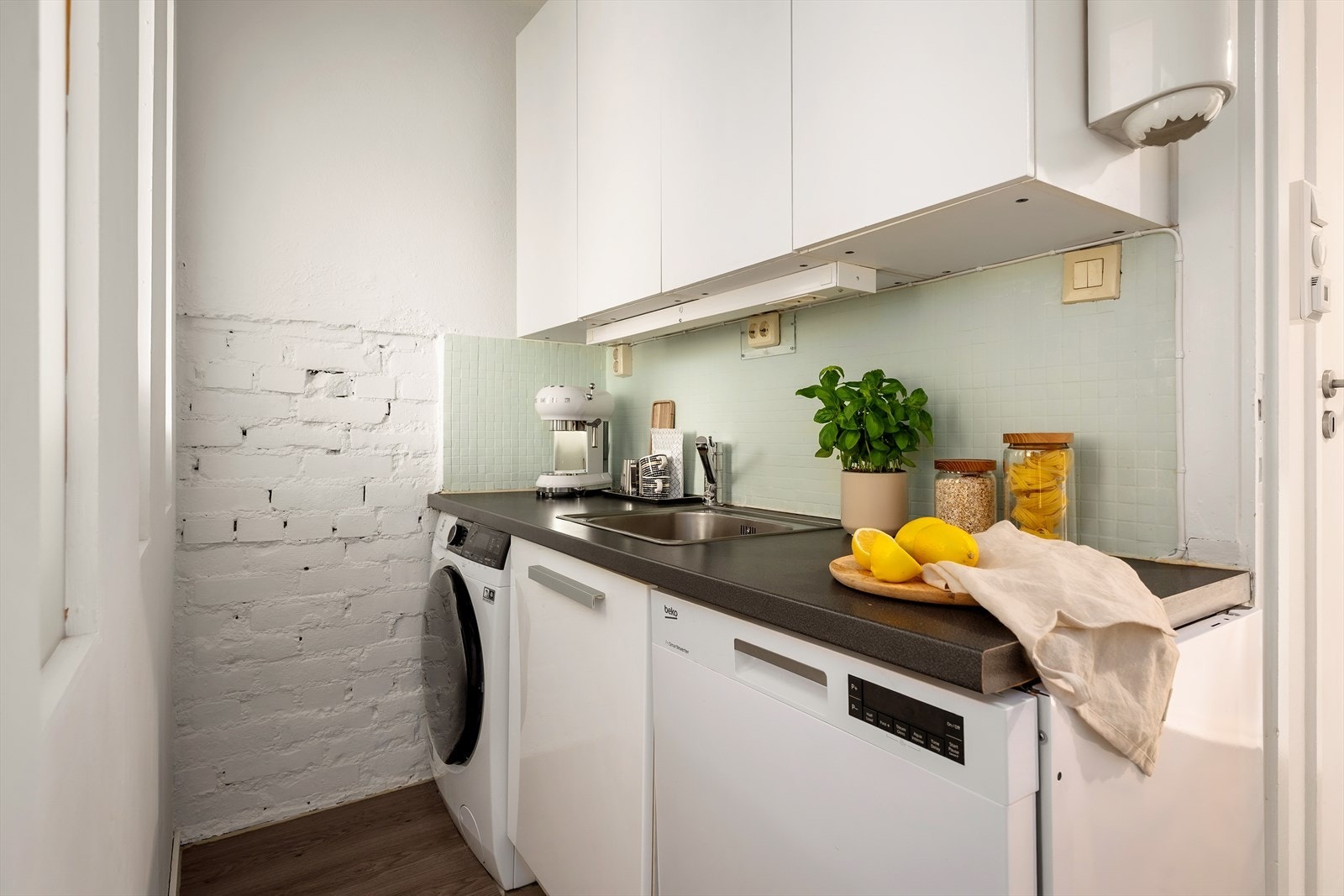 Praktisk del av kjøkkenet med opplegg for både vaskemaskin og oppvaskmaskin, for å optimalisere arealbruk. Galleribilde