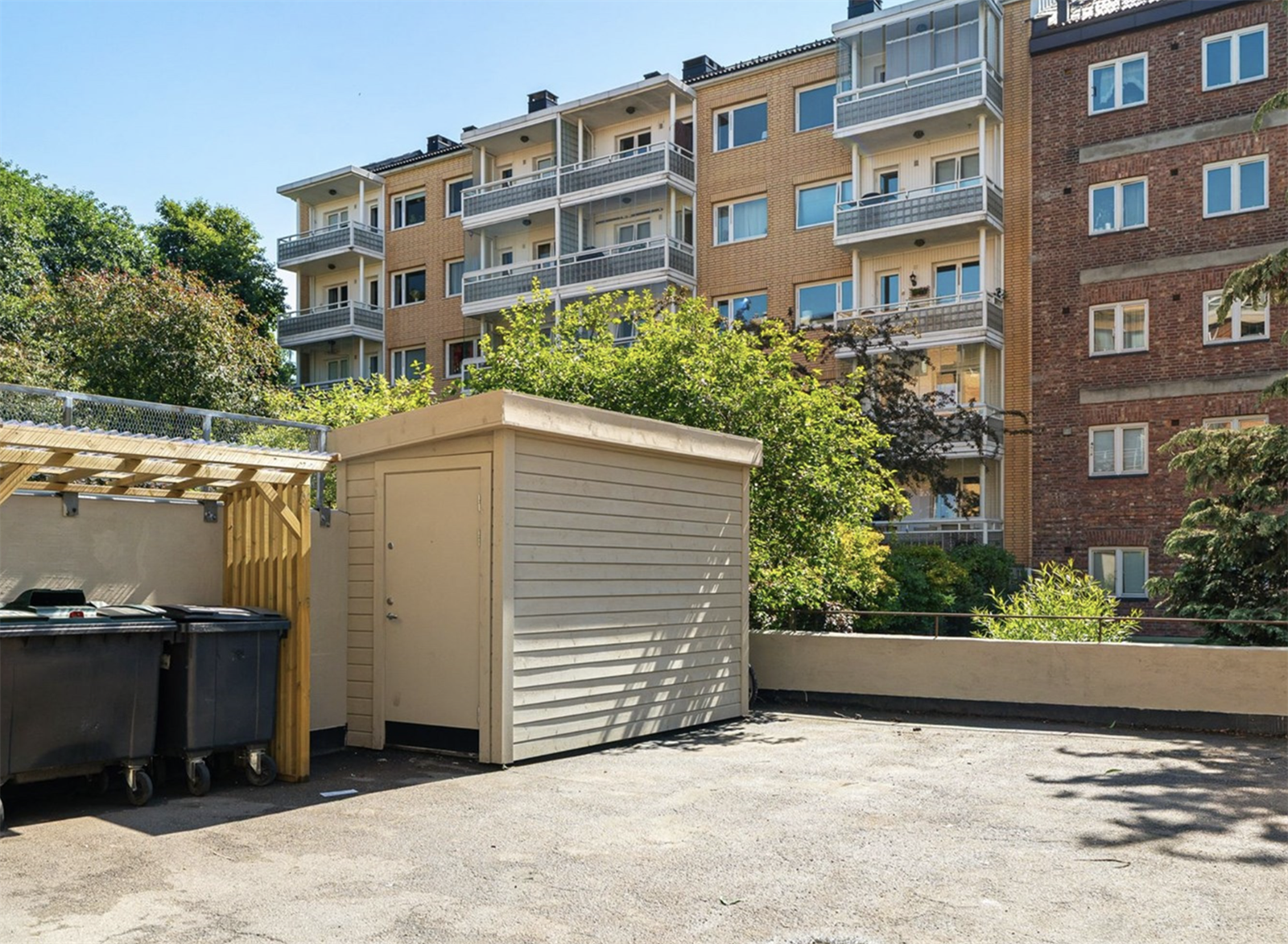 Bakgård med flere felles låsbare sykkelboder og parkering Galleribilde
