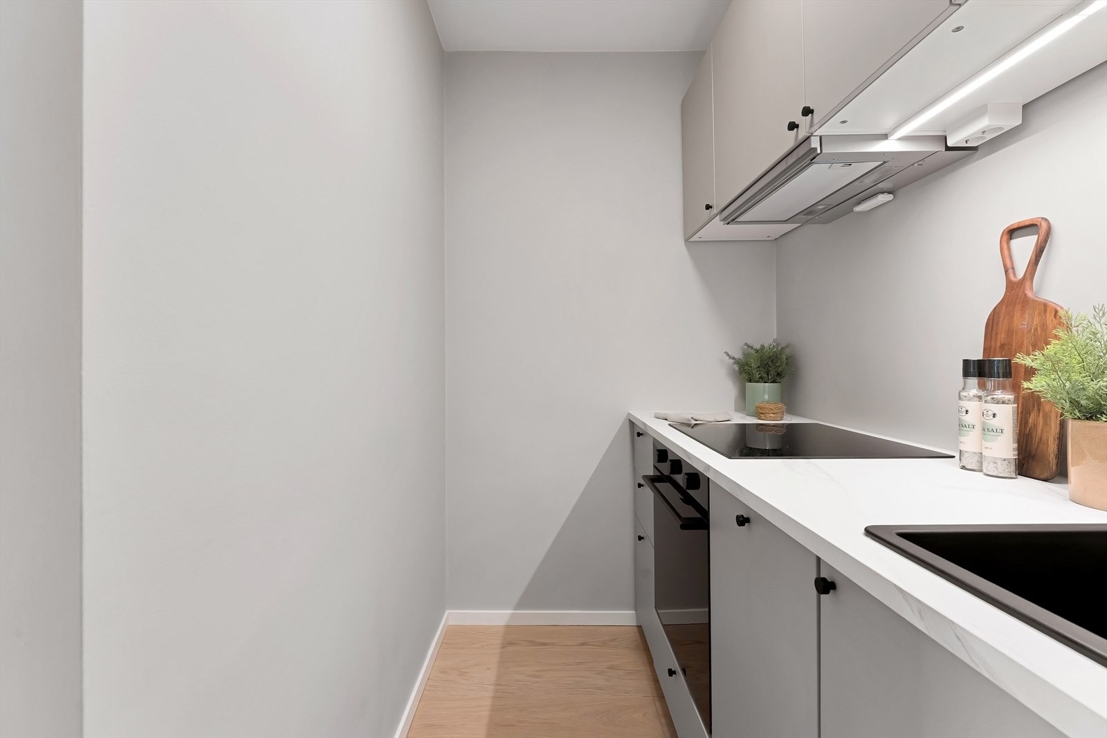 Kjøkkeninnredning med malte glatte fronter, laminat benkeplate, oppvaskkum i kompositt. Integrerte hvitevarer med induksjon platetopp, stekeovn, kombiskap (kjøl/frys) og oppvaskmaskin. Galleribilde