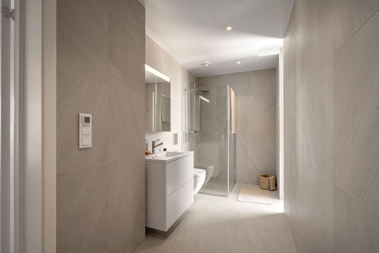 Badet med store, tidsriktige fliser på både gulv og vegger. Galleribilde