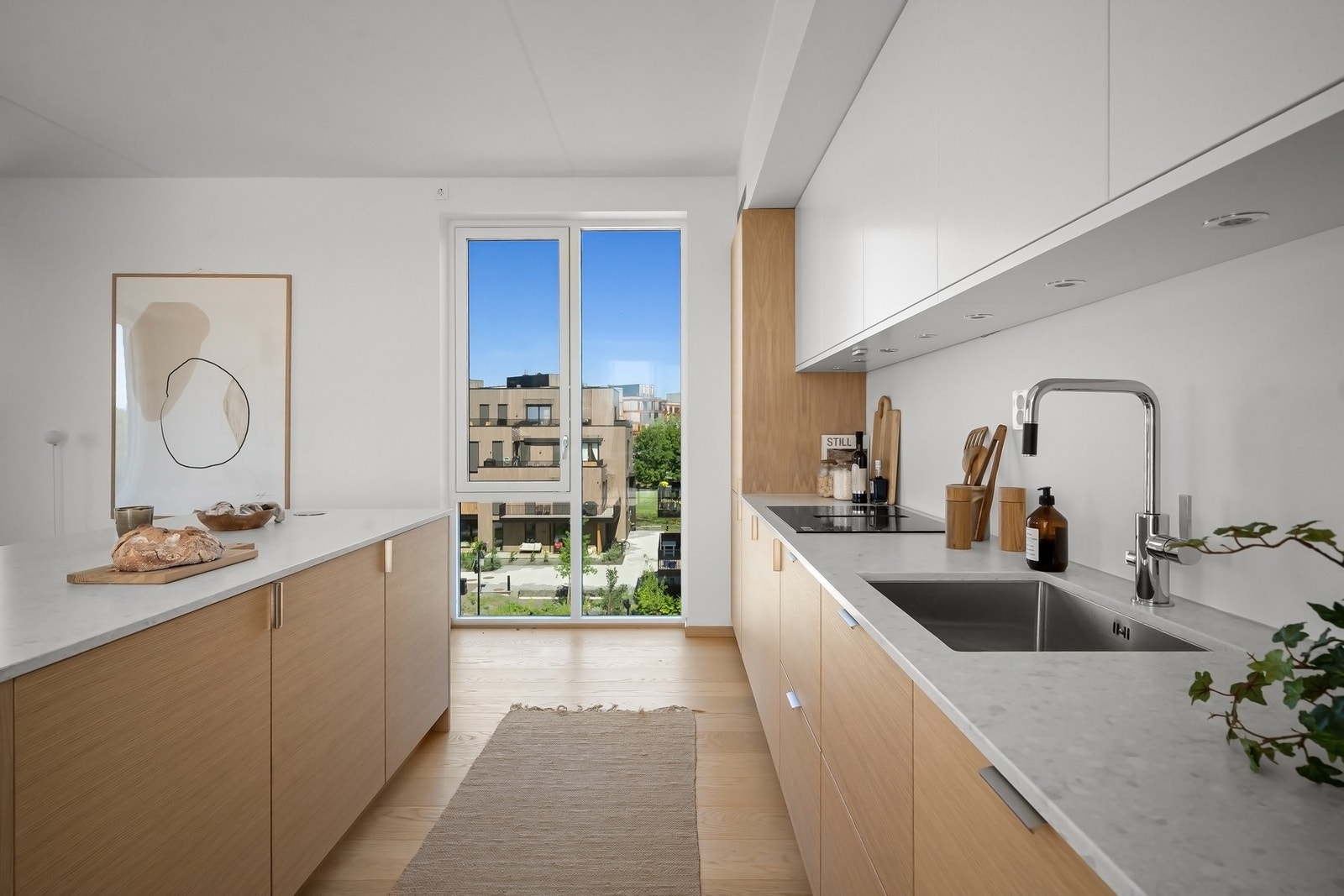 Lyst og moderne kjøkken med store vindusflater og utsikt mot grøntarealer. Galleribilde