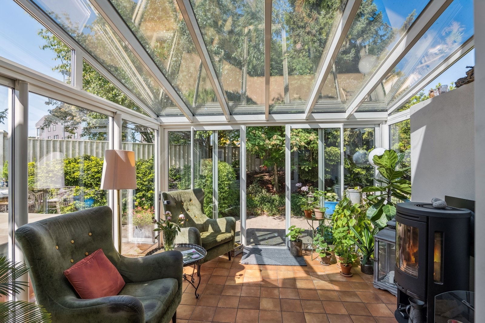 Innglasset vinterhage med fliser og varmekabler på gulv og en flott vedovn Galleribilde