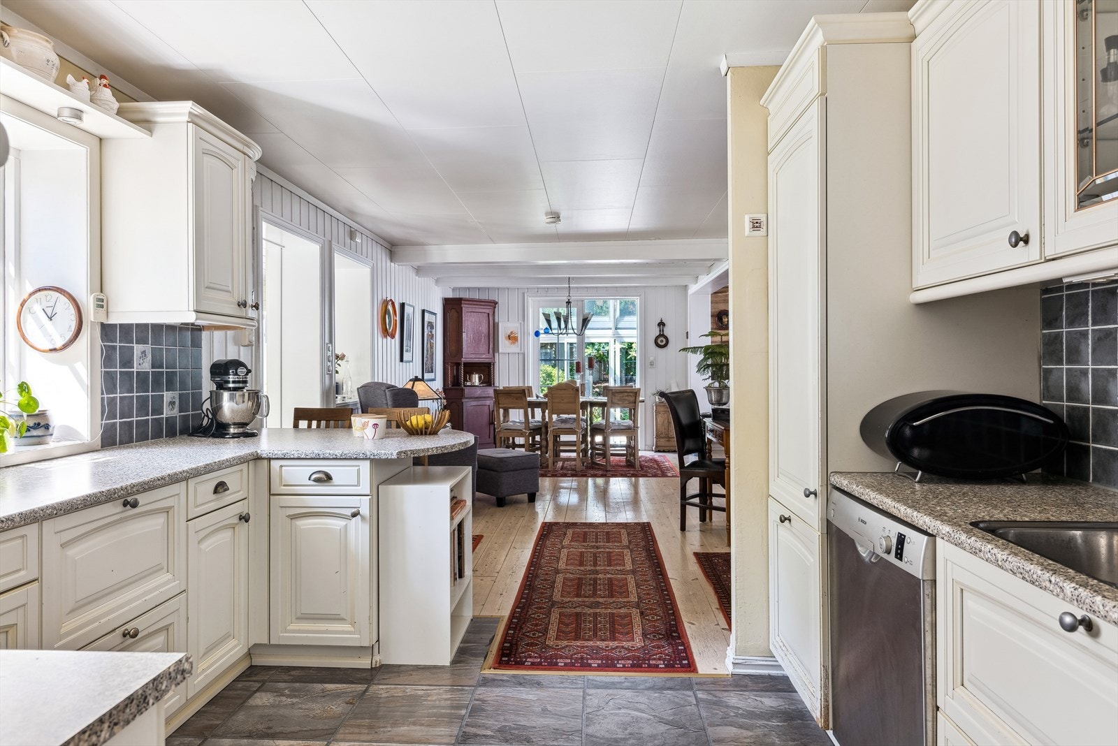 Hvit kjøkkeninnredning med profilerte fronter og benkeplate av laminat Galleribilde