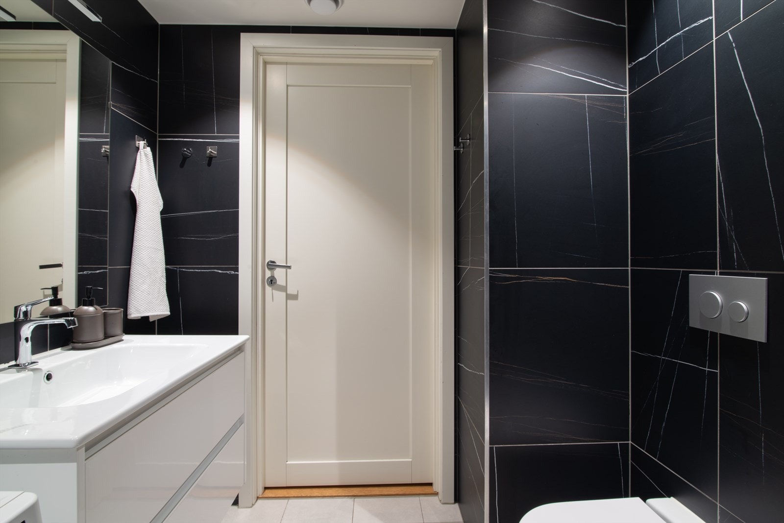 Badet er innredet med servant på servantskap, speil med lys, dusjhjørne og toalett. Galleribilde