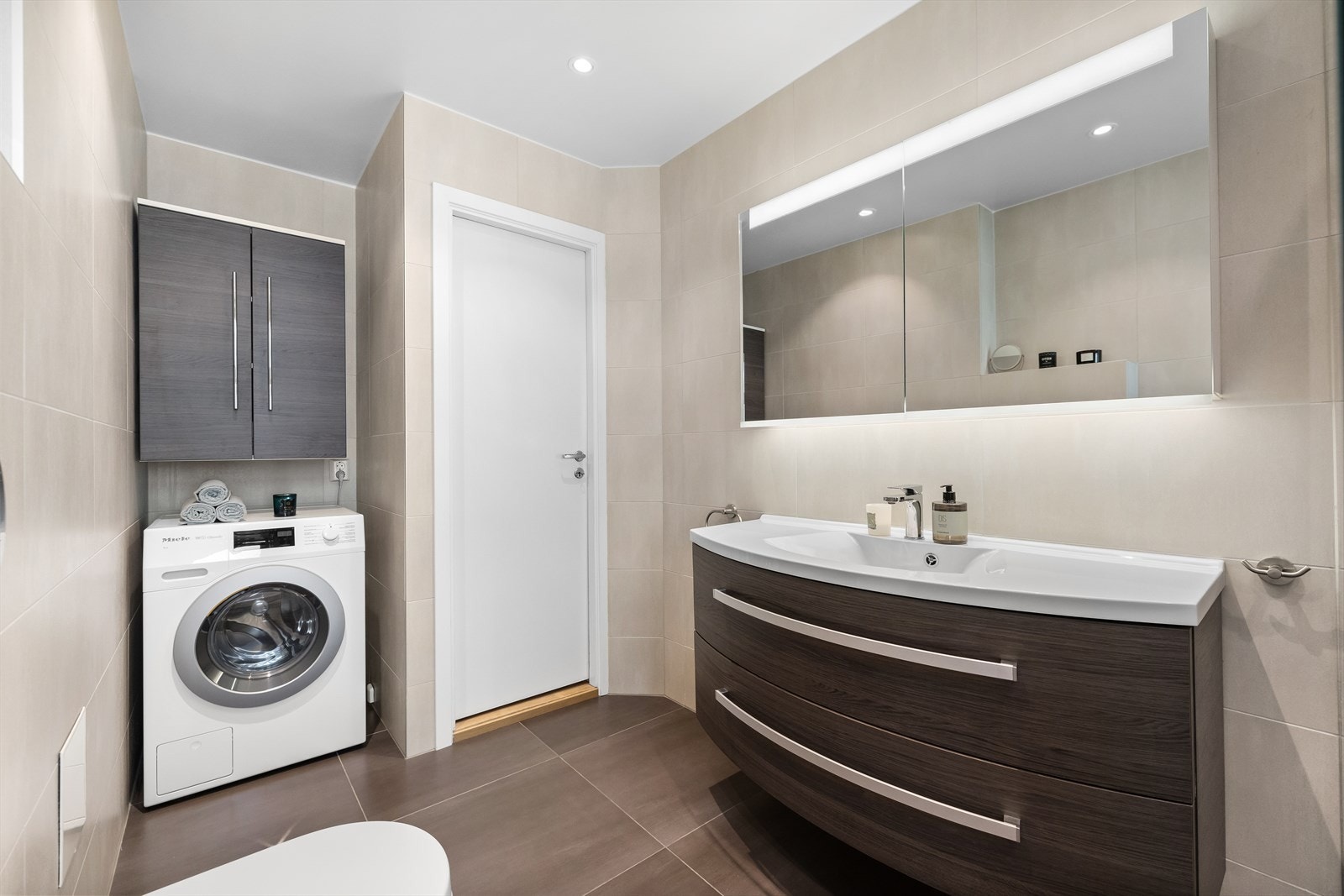 Innredningen består av servantskap med ettgreps blandebatteri, speilskap med lys, vegghengt toalett og dusjnisje med glassvegg og regnfalldusj Galleribilde