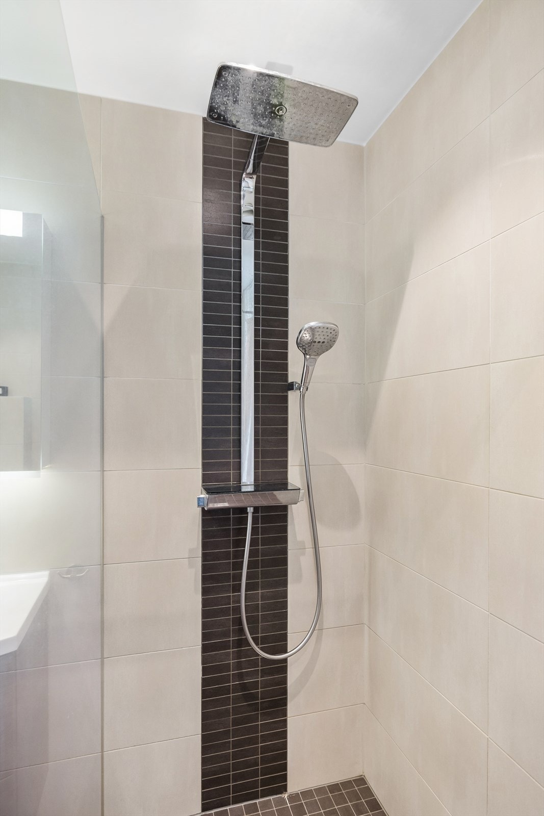 Badet har flislagte gulv og vegger, samt malt overflate i himling med downlights. Det er gulvvarme og opplegg for vaskemaskin Galleribilde