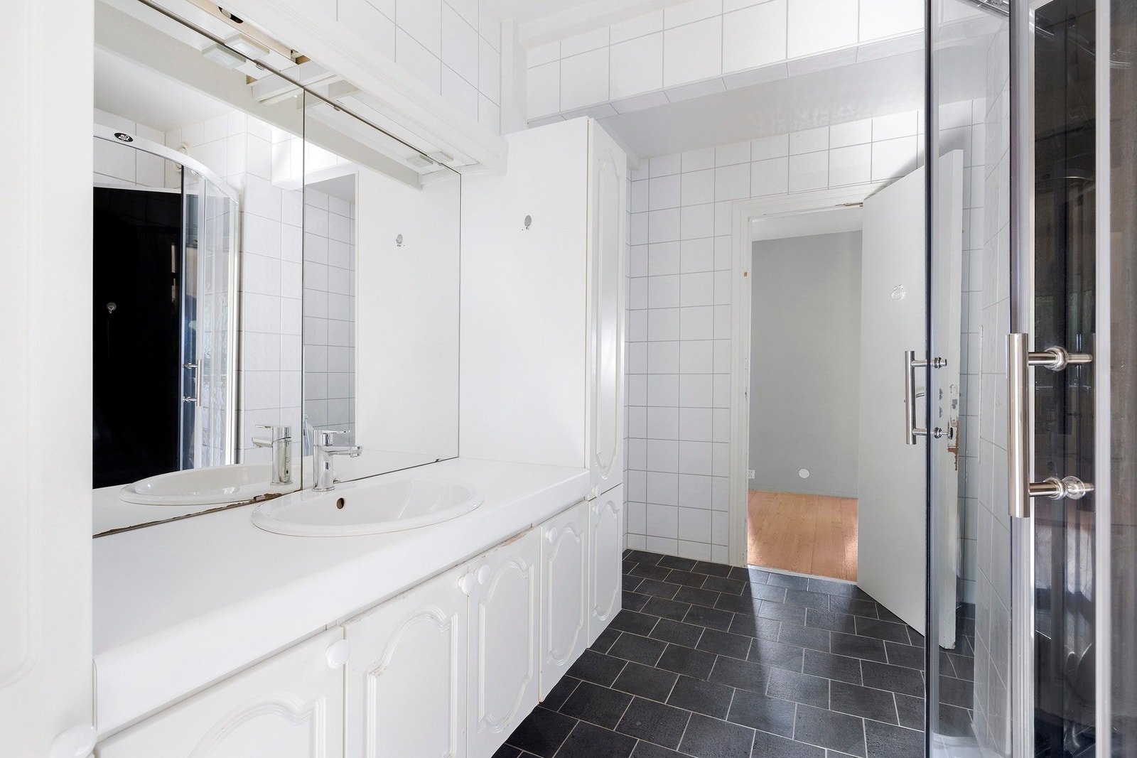 Flislagt bad med servantseksjon, dusjkabinett, gulvmontert toalett og speil. Galleribilde