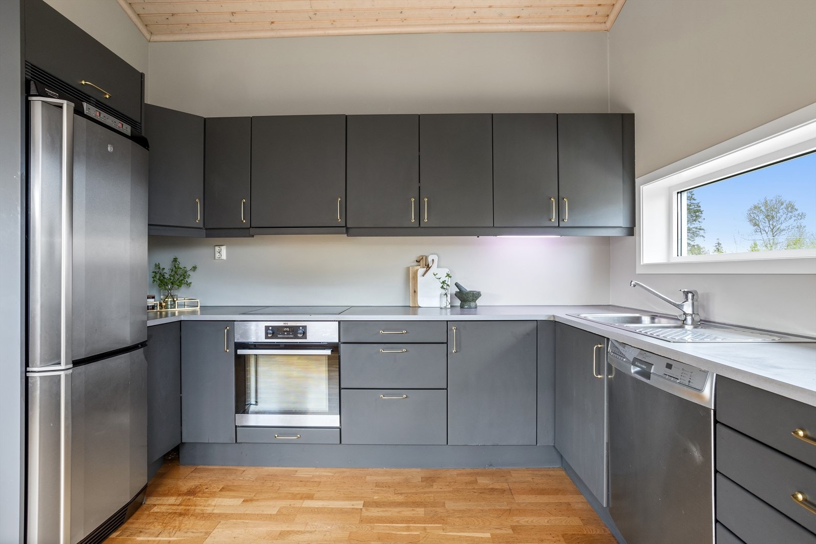 Kjøkkeninnredning med slette fronter. Laminat benkeplate. Integrert koketopp og stekeovn. Opplegg for oppvaskmaskin. Ventilator med utlufting. Galleribilde