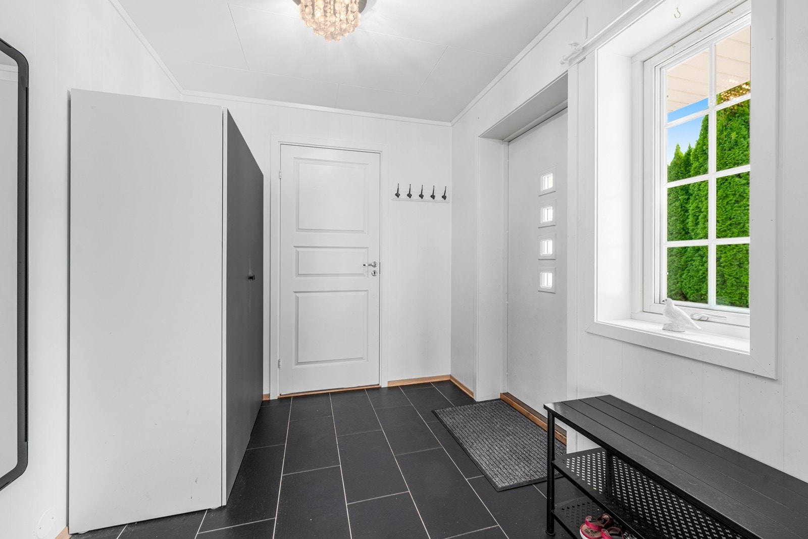 En romslig entré ønsker deg velkommen. Her kan du henge av deg jakken og ta av deg skoene før du tar turen videre i ditt nye hjem. Varmekabler i gulv. Inngang til praktisk innebod. Galleribilde