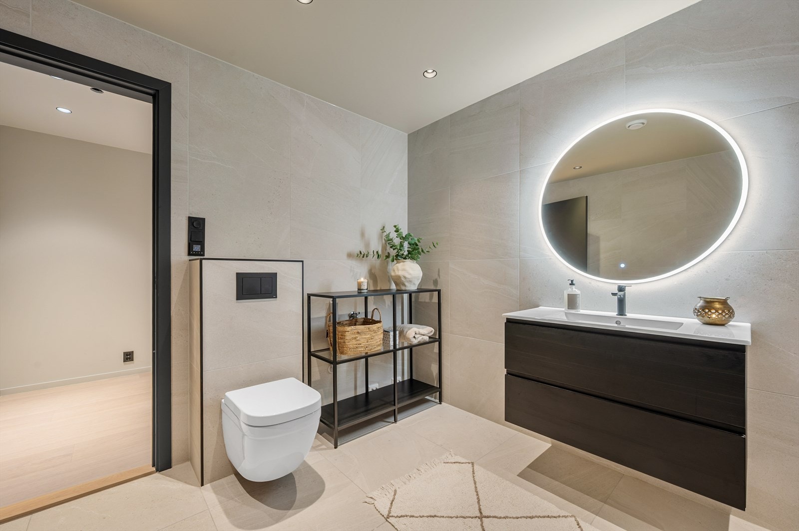 Badet inneholder baderomsinnredning i sorte farger, vegghengt toalett, opplegg for vaskemaskin Galleribilde