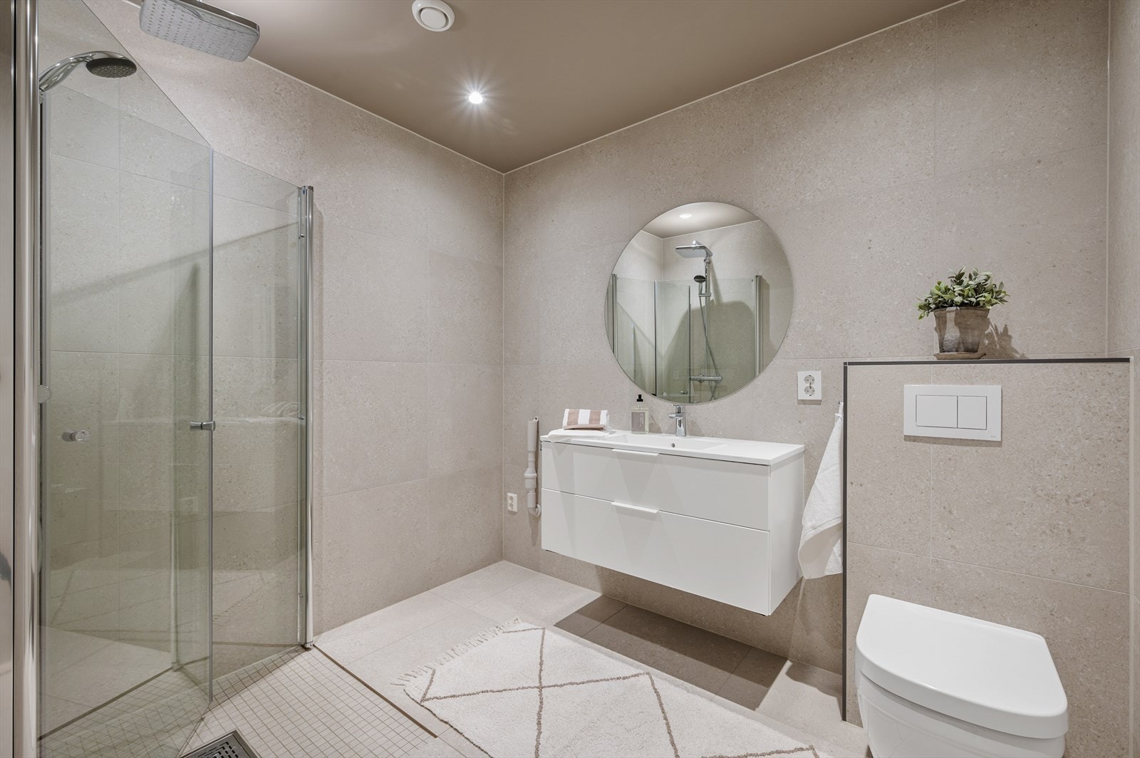 Badet har en baderomsinnredning med servant, dusjhjørne, vegghengt toalett og opplegg for vaskemaskin Galleribilde