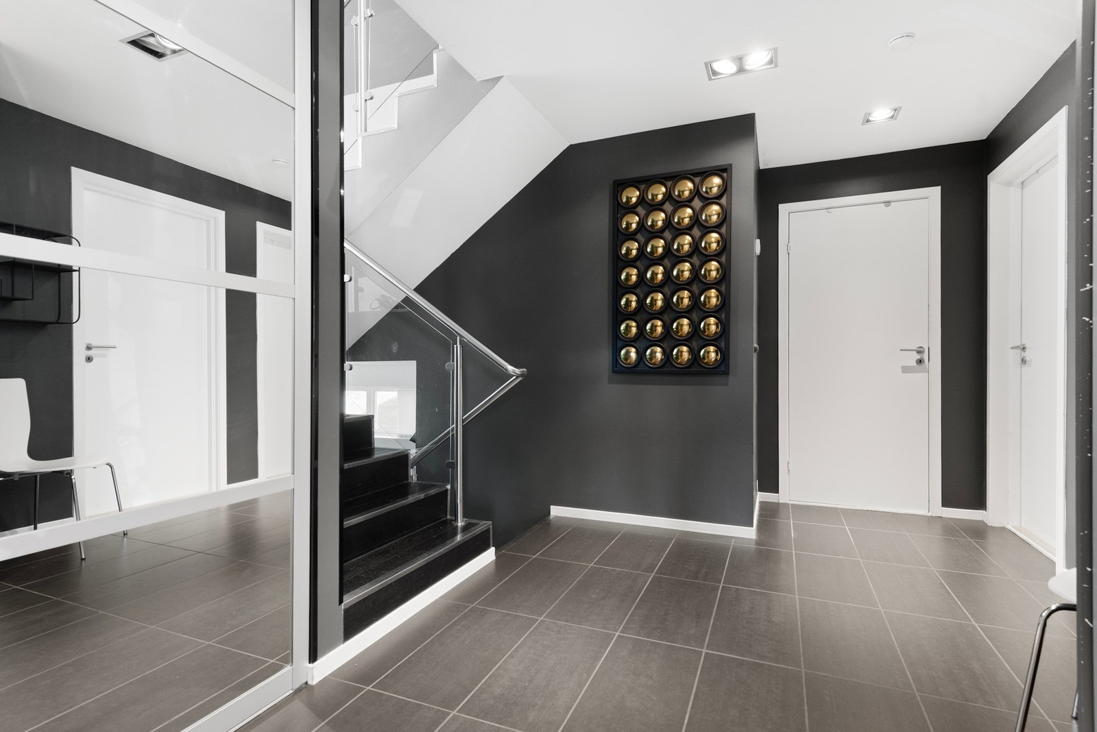 Her kommer du inn i flislagt entré med romslig skyvedørsgarderobe - speildører i garderoben gir en åpen og innbydende følelse Galleribilde