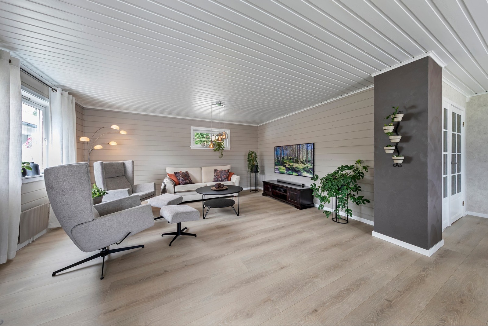 Hoveddelen i våningshuset har stue med laminatgulv og malt panel på vegger Galleribilde