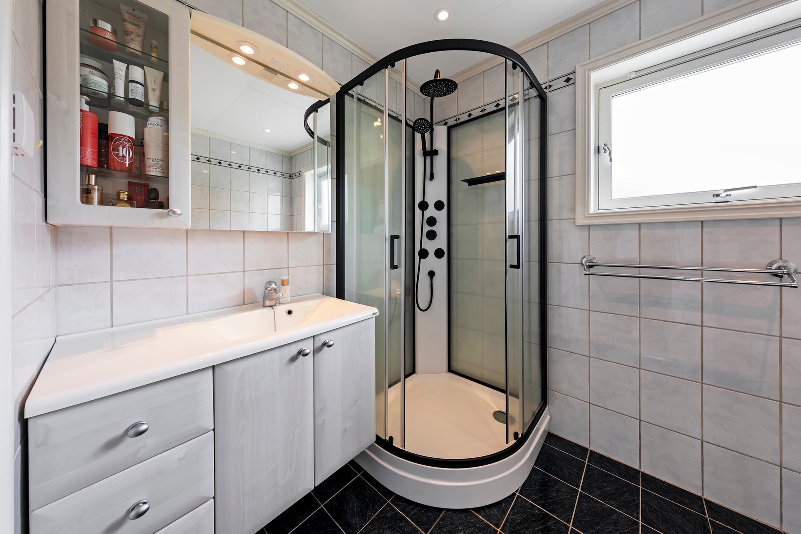 Badet har flislagt gulv med varmekabler. Foliert innredning med nedfelt servant, gulvstående toalett og dusjkabinett Galleribilde