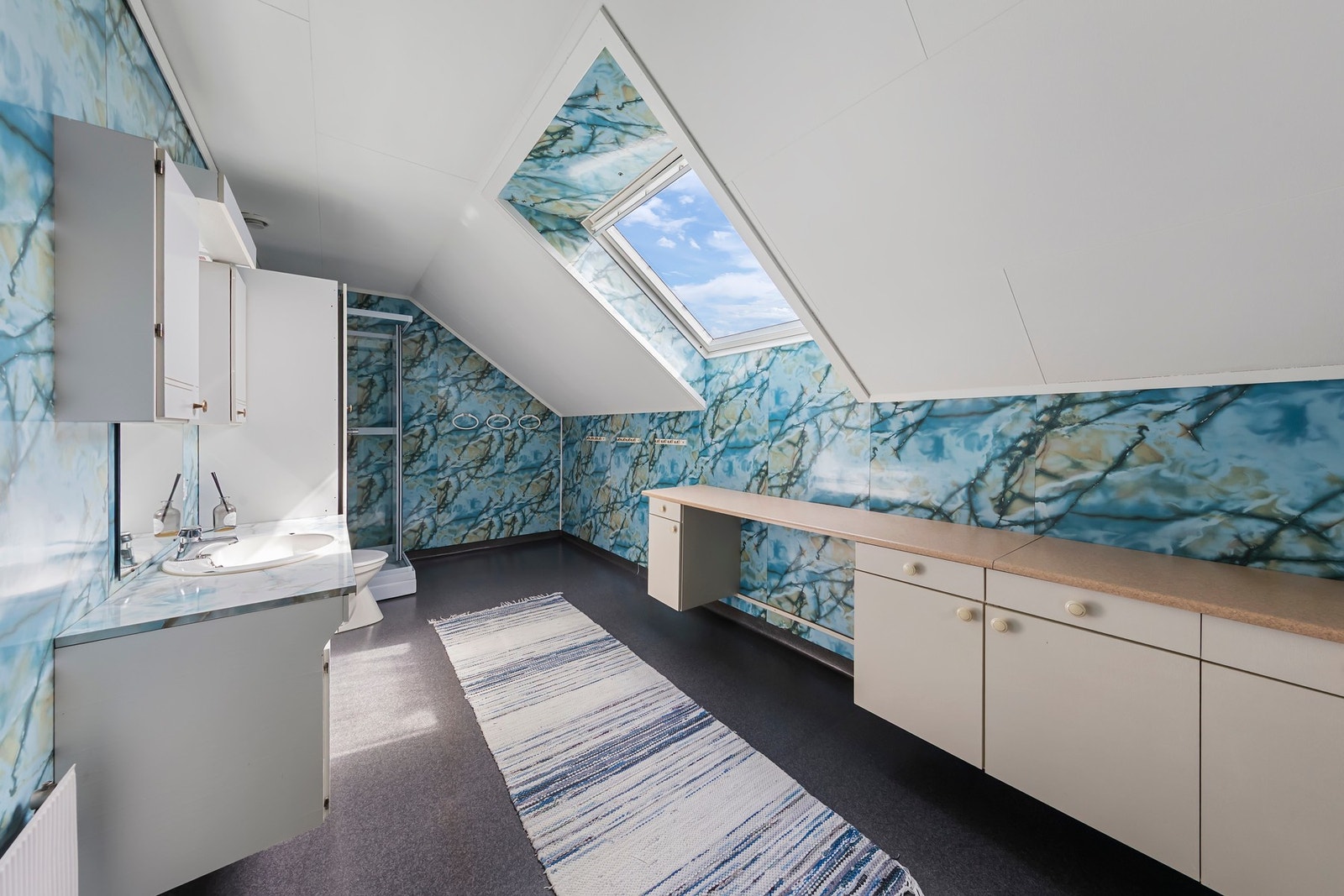 Bad på loft har vinylbelegg på gulv med elektriske varmekabler. Foliert innredning og benkeplate i laminat Galleribilde