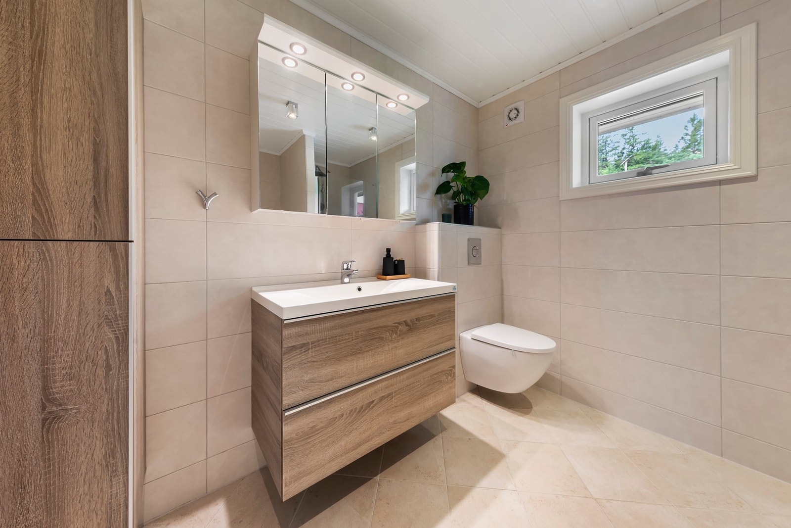 Badet har flislagt gulv og vegger, elektriske varmekabler i gulv. Foliert innredning med heldekkende servant, speilskap Galleribilde