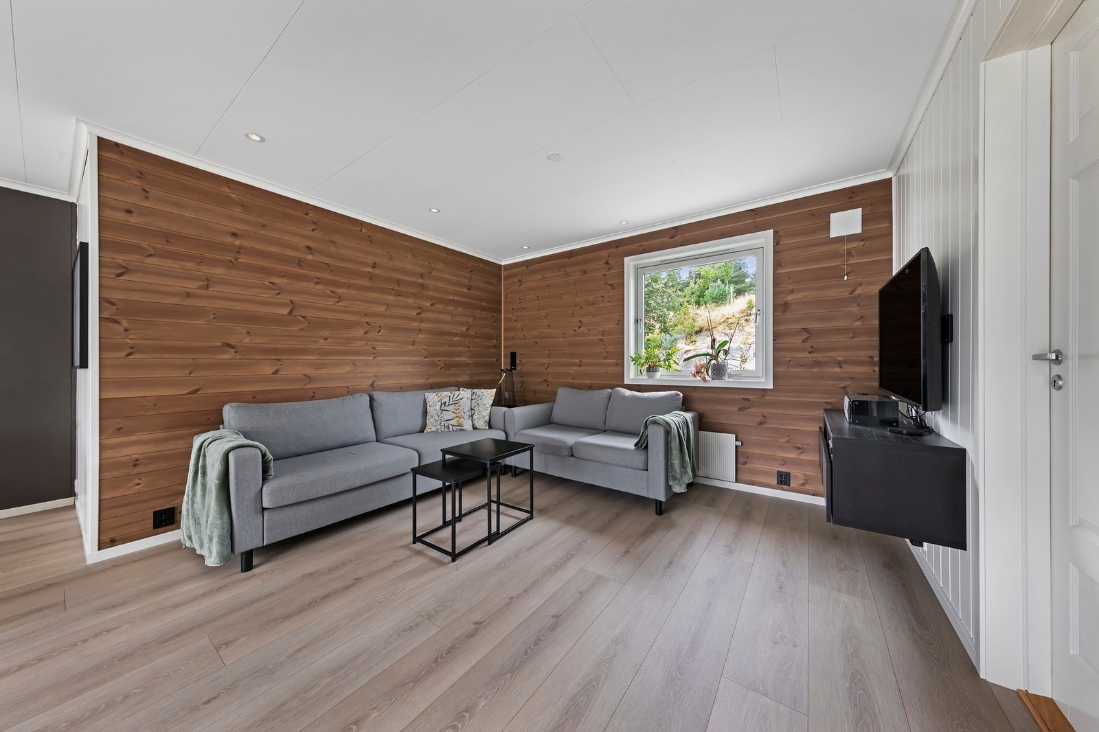 Stuen har laminat på gulv og malt panel og plater på vegger Galleribilde