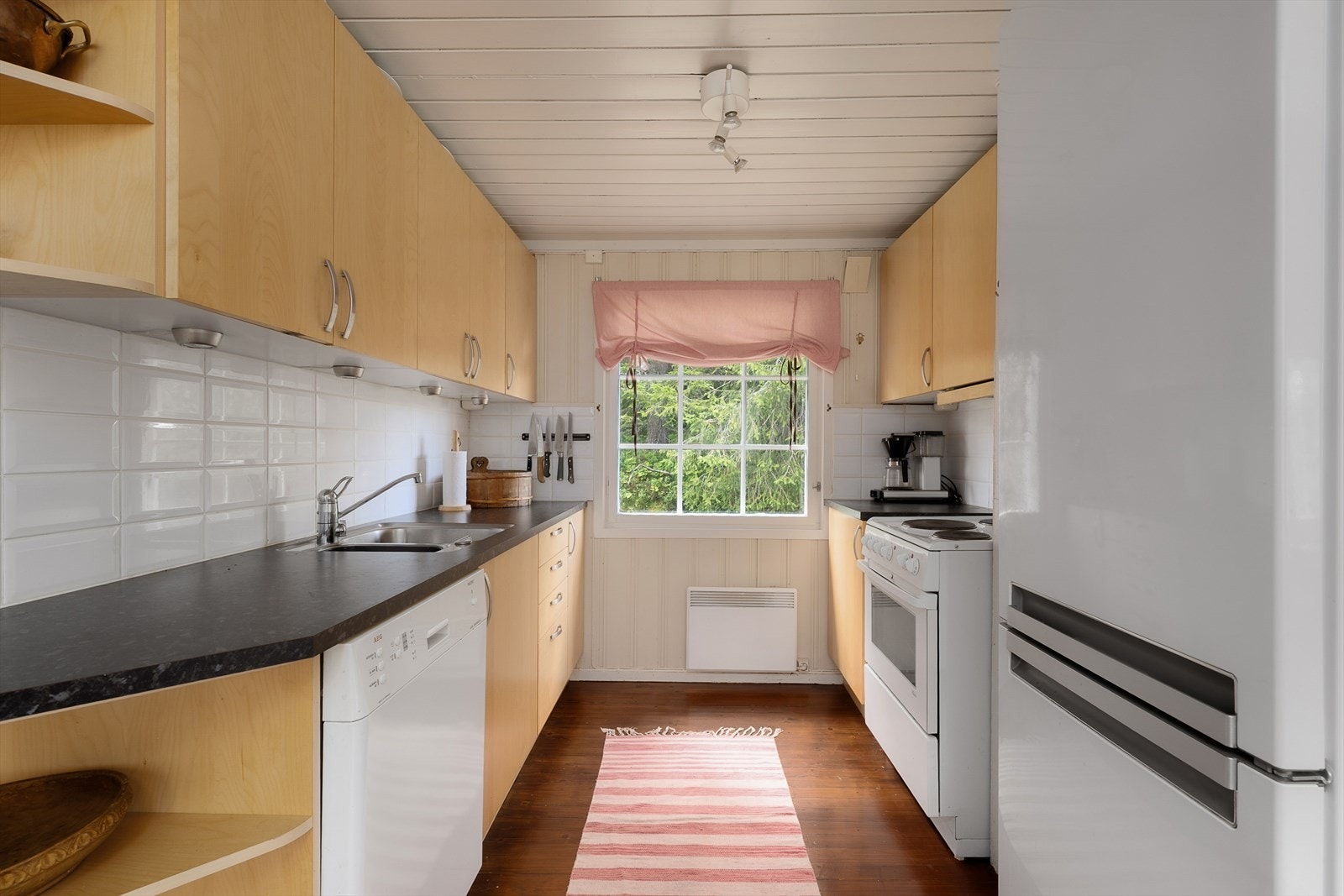 Lyst kjøkken med over- og underskap og arbeidsflater på benkeplate Galleribilde