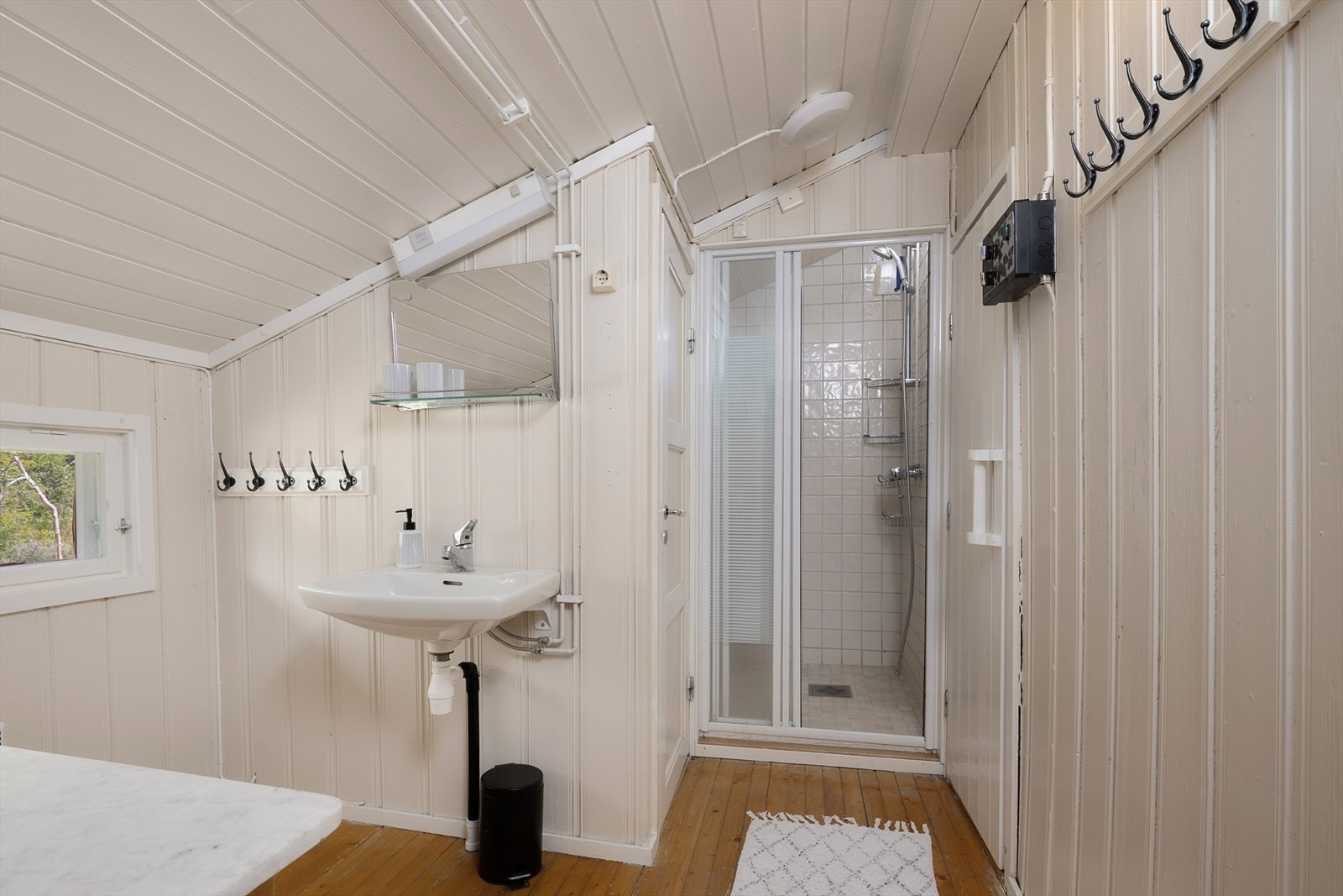 Hyttbad med vegghengt servant, dusjhjørne og tilgang til wc-rom og badstue Galleribilde