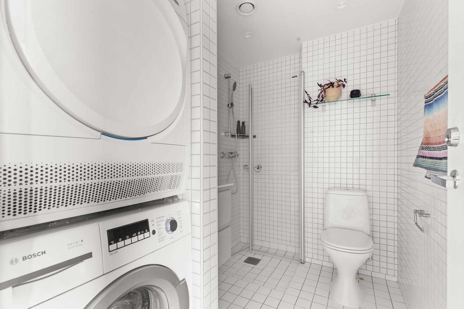 Lyst og pent flislagt baderom. Badet har innfellbare dusjdører, wc, servant og speil. Samt opplegg for vaskemaskin og tørketrommel. Galleribilde