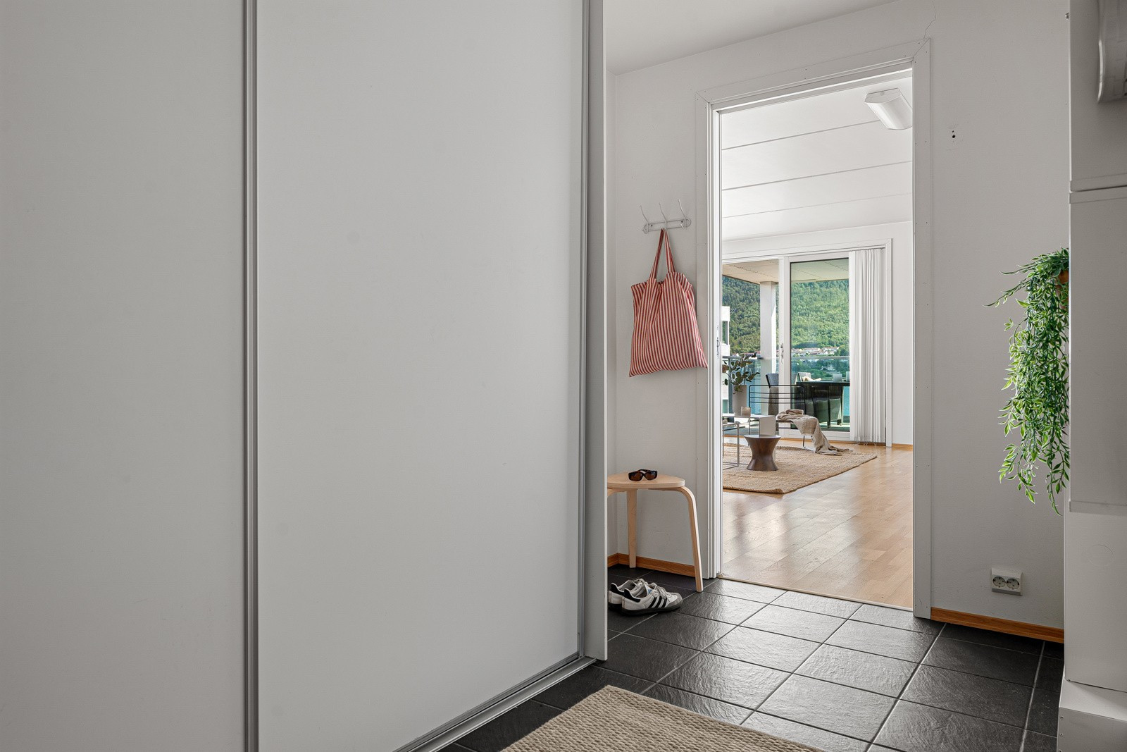 Romslig entre med fliser på gulv og skyvedørsgarderobe som sikrer oppbevaringsplass for yttertøyet.