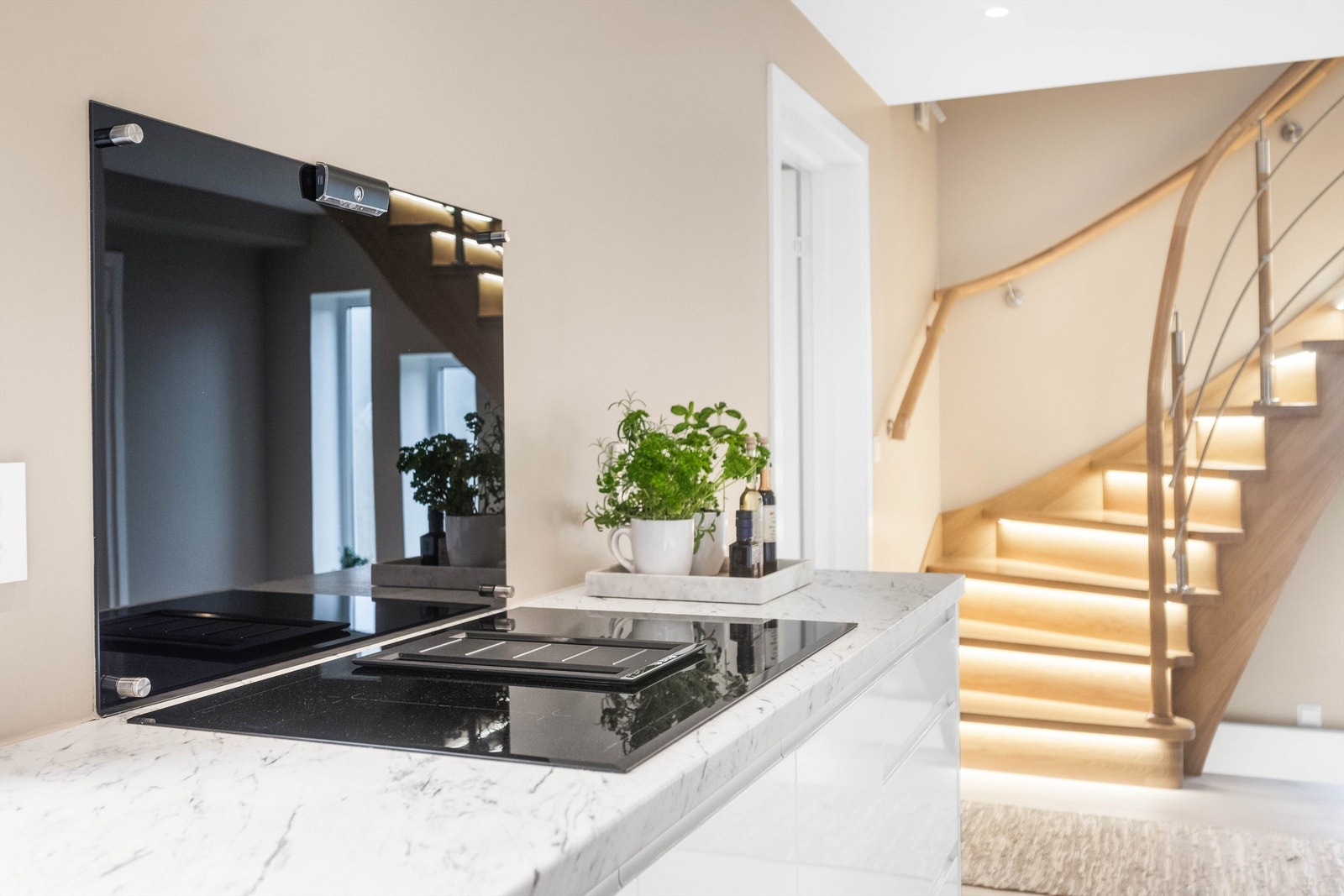 Kjøkkenet er innredet med laminat benk med sponkjerne, slette hvite fronter i høyglans, nedfelt kum med ett-greps blandebatteri, nedfelt platetopp og kullfilter-vifte. Galleribilde