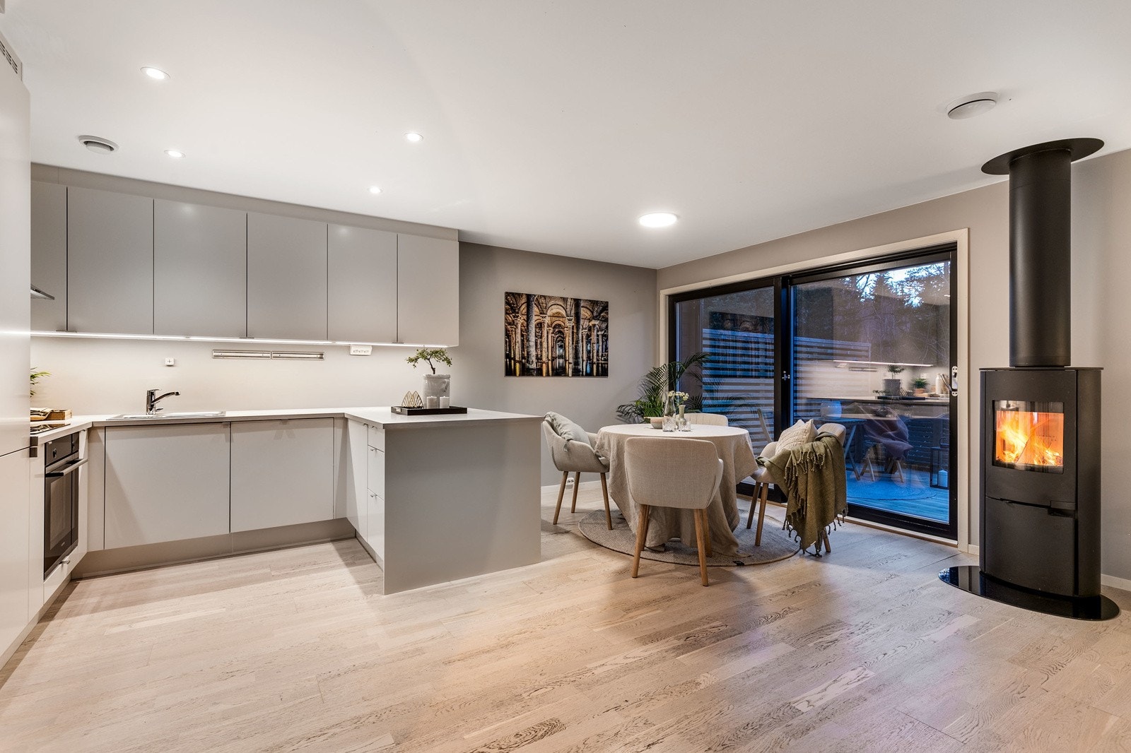 Stilrent og moderne Sigdalkjøkken i åpen løsning. Kjøkkenet er utformet i praktisk vinkelløsning, som gir godt med benke- og arbeidsplass. Innredningen består av lyse slette fronter med foring opp til tak og laminert benkeplate med nedfelt vaskekum. Galleribilde