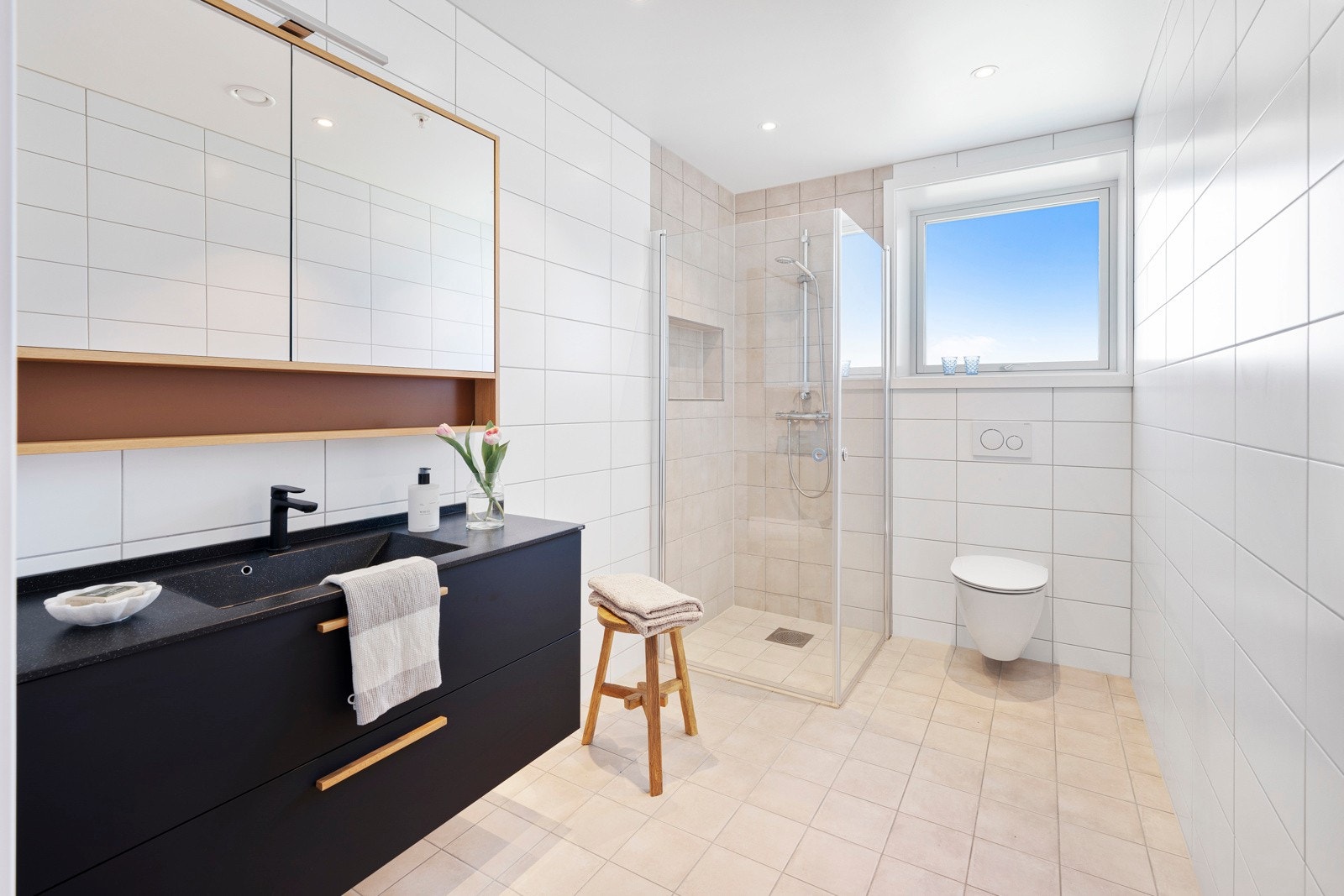 Bad 2 har hvite fliser på veggene, downlights i himlingen og lyse fliser på gulv med vannbåren gulvvarme. Galleribilde