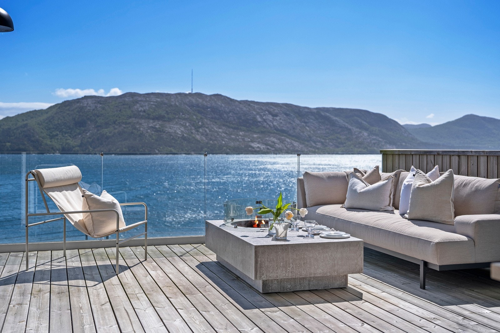 Terrassen har god plass til grill og ønsket utemøblement på dekket av tre, og det hele rammes inn med rekkverk i glass som ivaretar utsikten på beste måte. Galleribilde