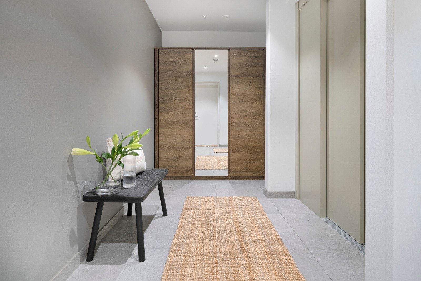 Vel oppe blir vi ønsket velkommen i en fin gang med lysmalte vegger og lysegrå fliser på gulv med vannbåren gulvvarme. Galleribilde