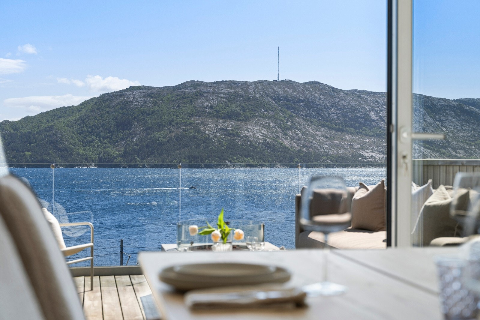 Stuen ligger i åpen løsning med kjøkkenet og spisestuen, og sammen danner de et stort, stilfullt allrom med luftig takhøyde, unik, naturlig lyssetting og misunnelsesverdig fjordutsikt. Galleribilde