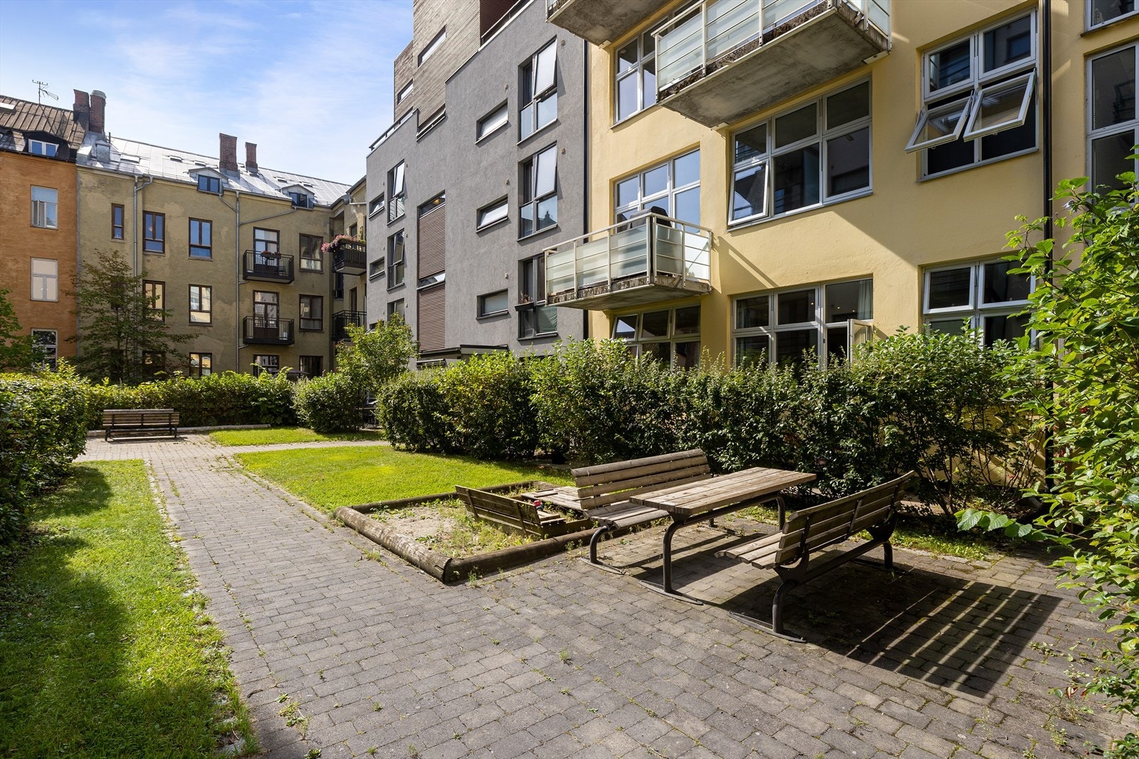 Borettslaget har en frodig bakgård med plen, beplantning og brostein. Galleribilde