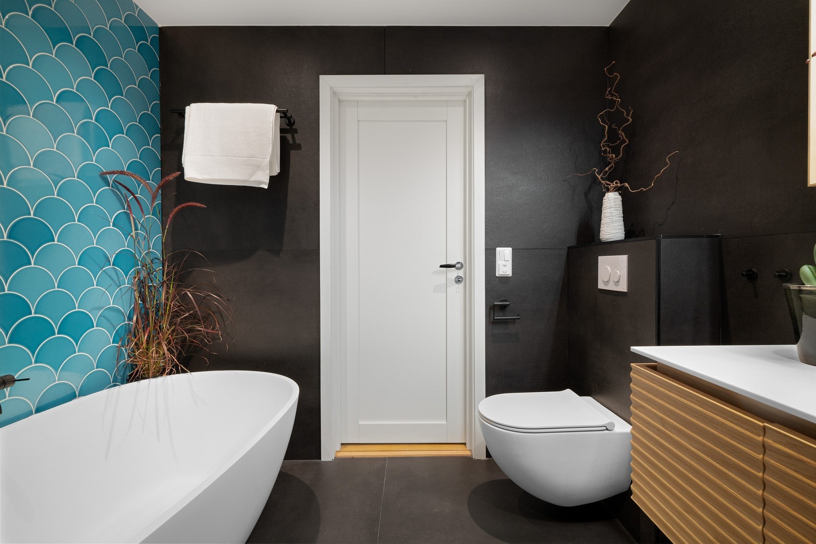 Corian servantbenk, designbadekar, veggklosett og dusj med glassvegg. Praktisk nisje med opplegg for vaskemaskin. Galleribilde