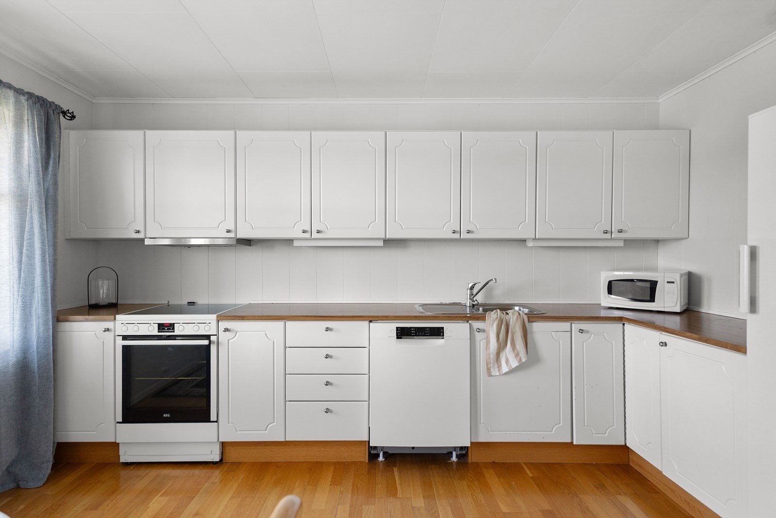 Kjøkkeninnredning med lyse profilerte fronter og benkeplate i laminat Galleribilde