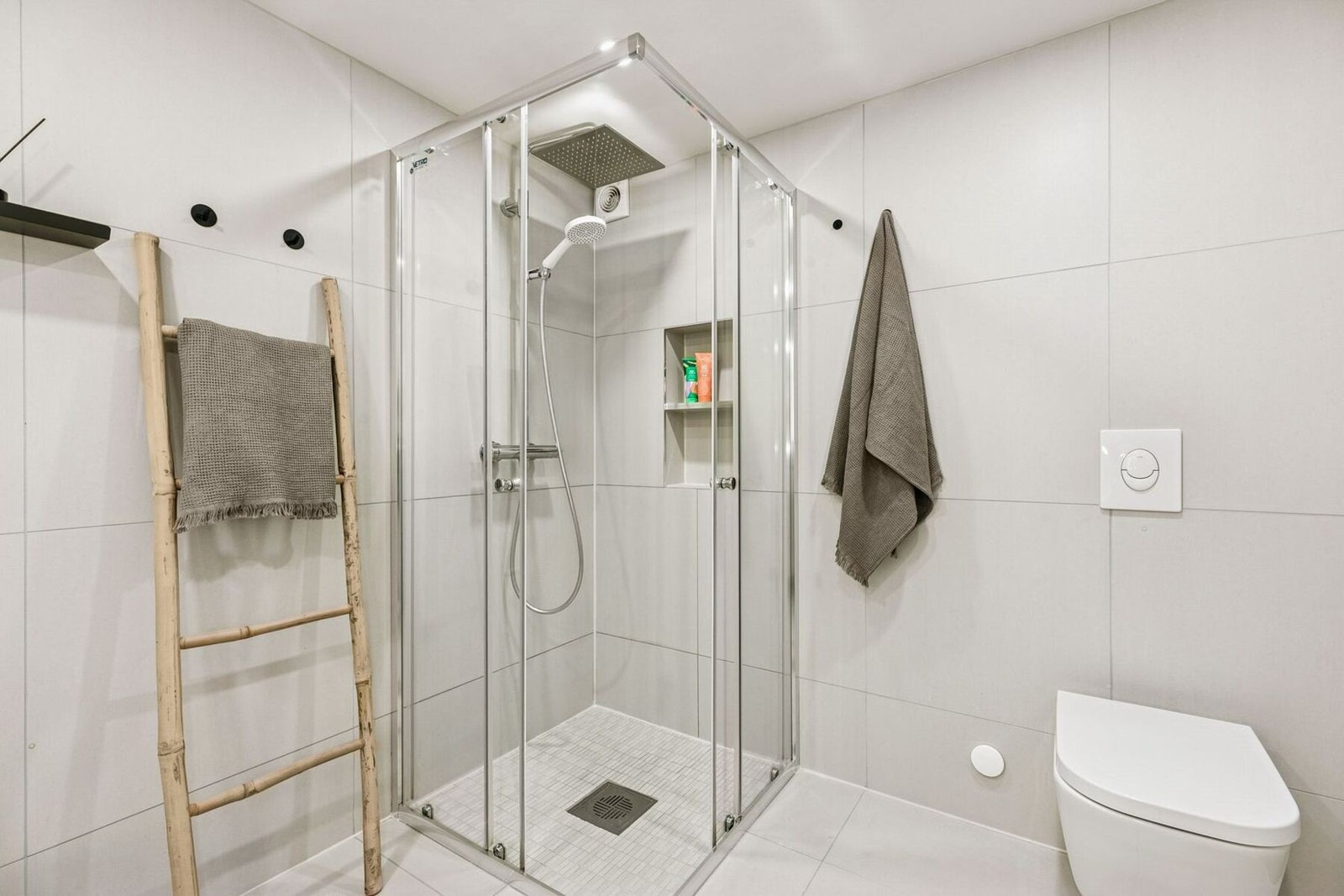 Dusjsonen består av dusjhjørne med herdet glassdører, regnfalldusj, hånddusj og en praktisk integrert hylle i veggen for dusjprodukter. Galleribilde