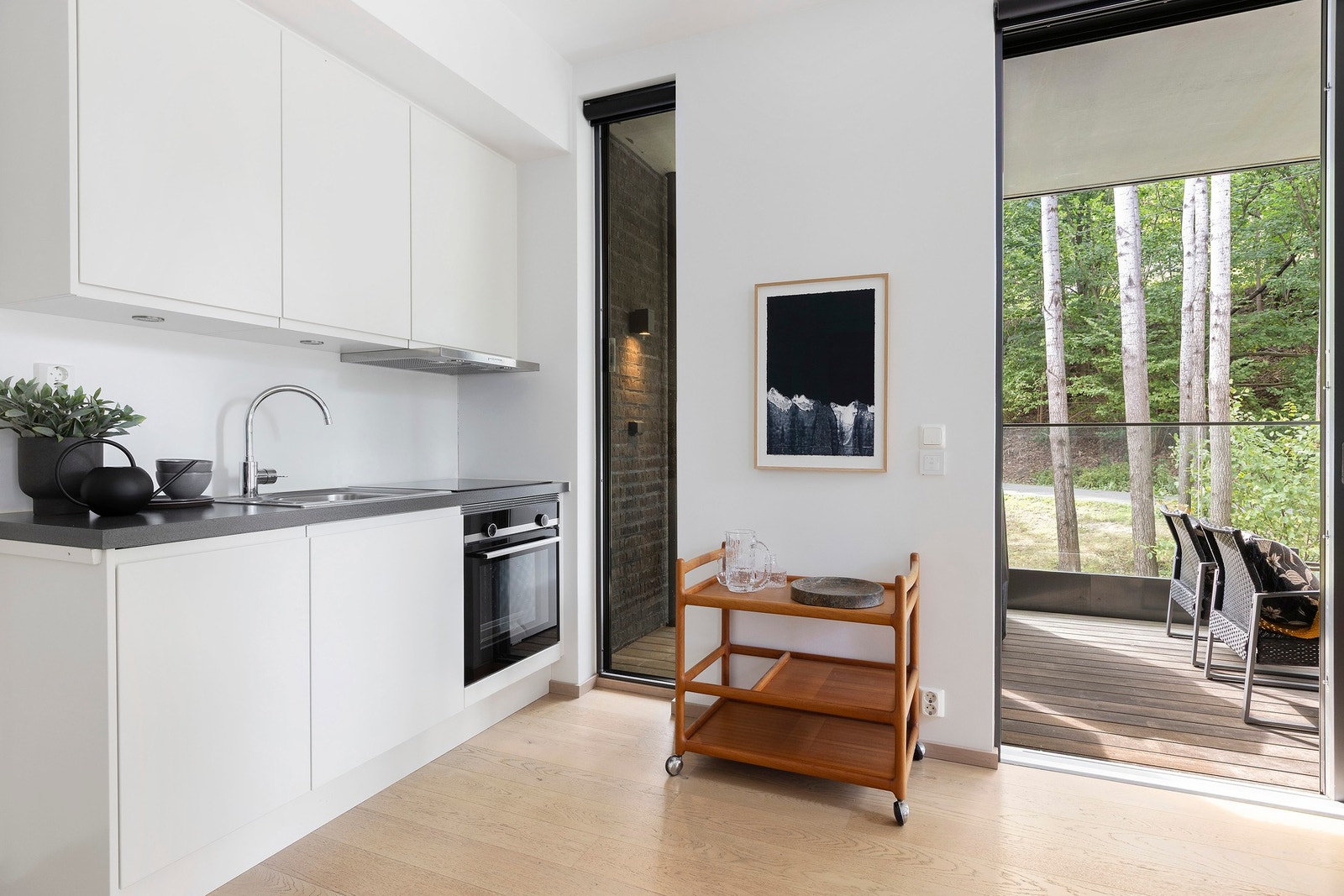 Stilren kjøkkeninnredning med integrerte hvitevarer og rikelig med skap- og benkeplass Galleribilde