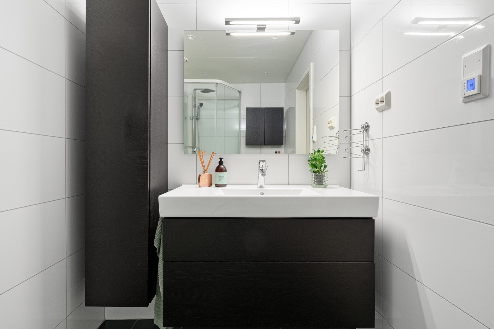Badet er innredet med nedfeldt servant og speilskap, vegghengt toalett med innebygget sisterne.