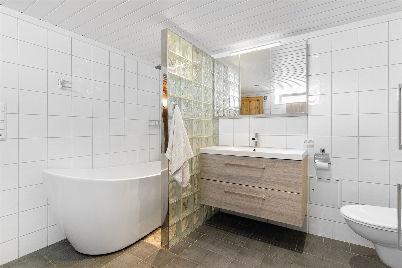 Badet er fra ca 2015, med innredning med nedfelt servant, veggmontert toalett, badekar, dusjvegger/hjørne. Galleribilde