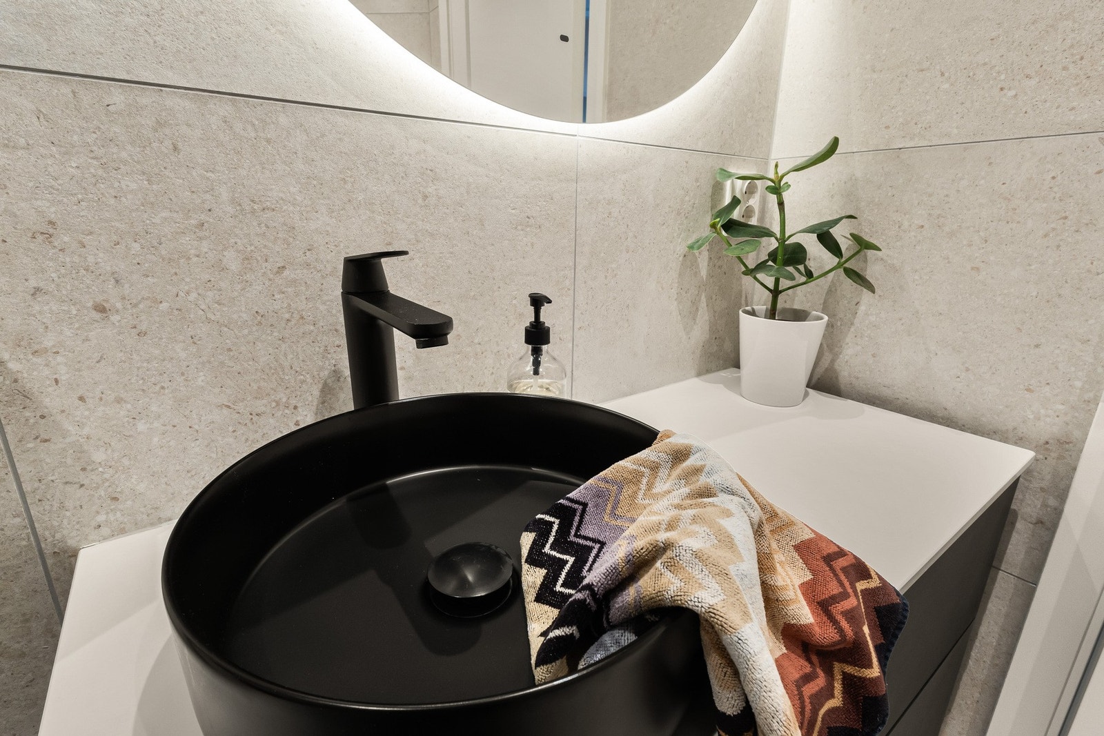 Badet er helfliset i en stilren beigetone, har sorte detaljer og gulvvarme. Galleribilde