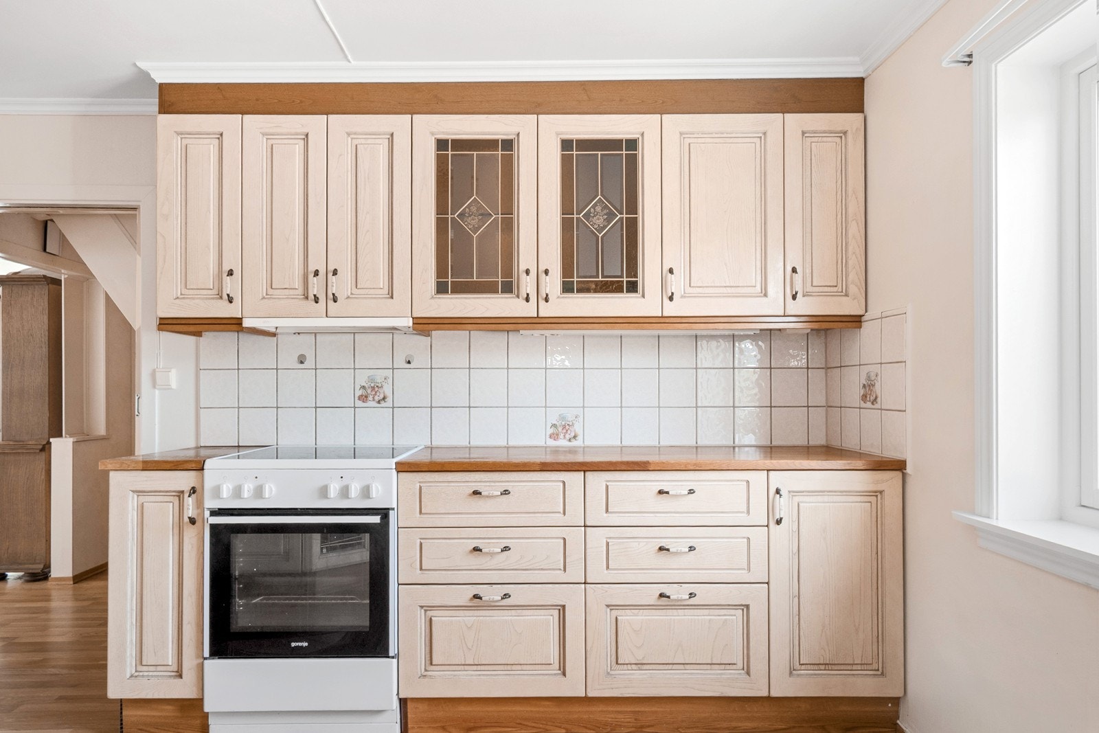 Innredningen har profilerte fronter, delvis vitrineskap og heltre benkeplate, samt fliser på vegg over benk. Galleribilde