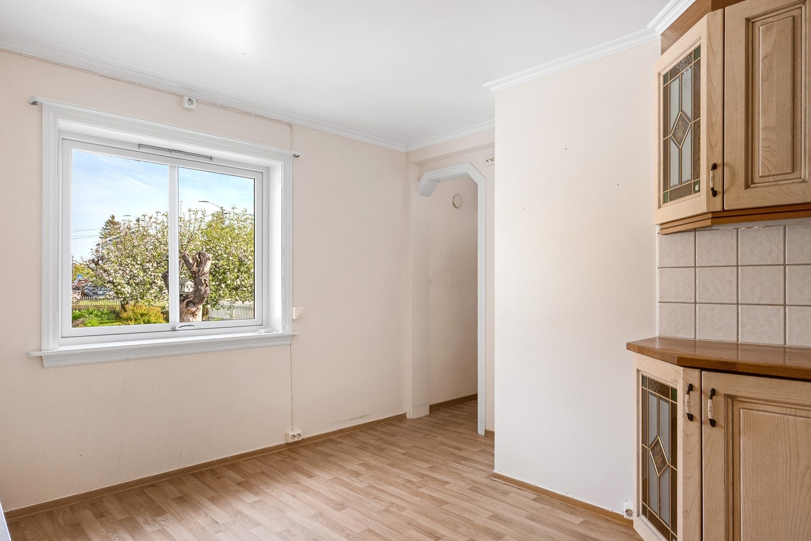 Et stort vindu gir naturlig lys og utsyn mot hyggelig hage. Innerst i rommet er et praktisk åpent kott/matbod. Galleribilde