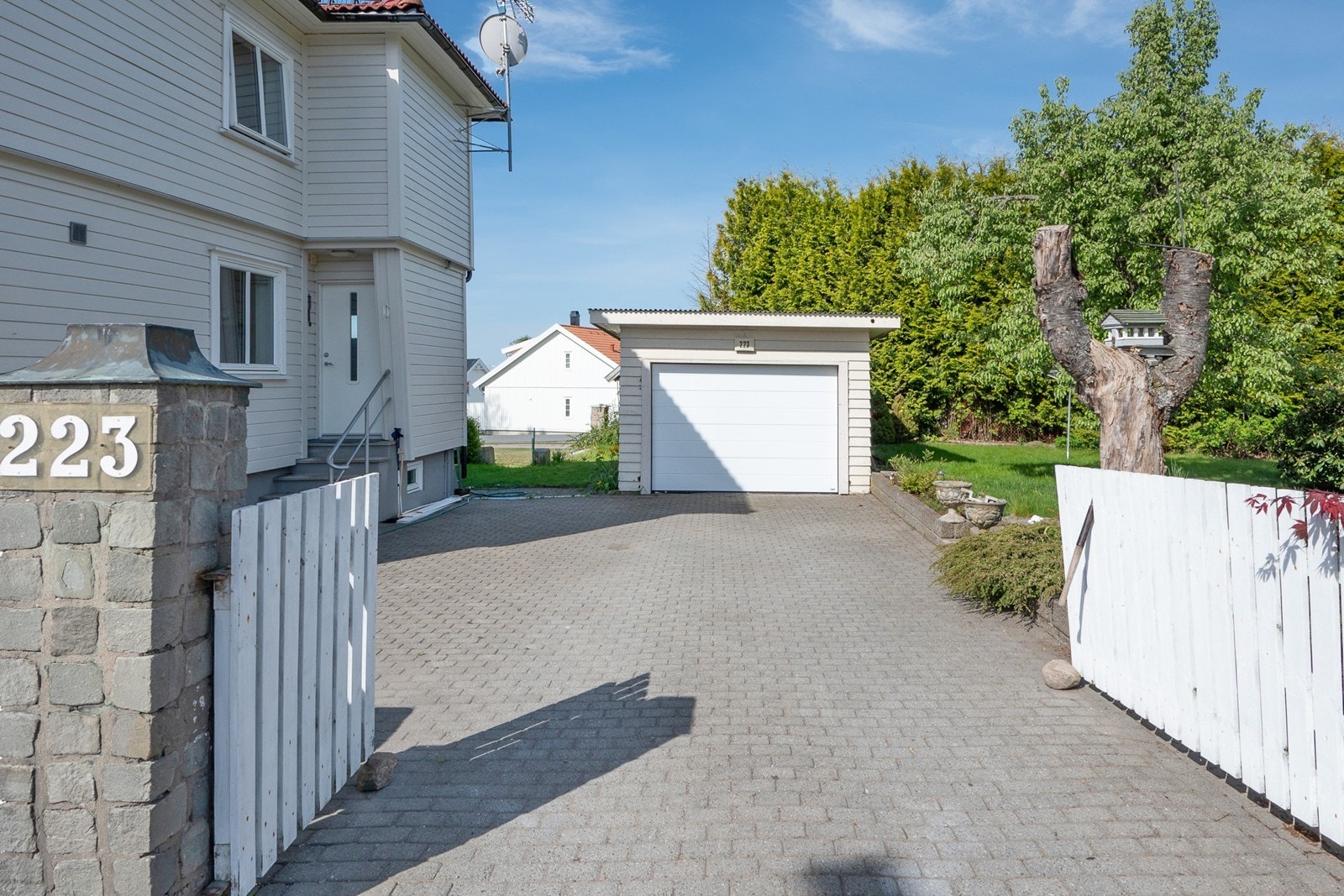 Frittstående garasje og gårdsplass med belegningsstein for plass til flere biler. Galleribilde