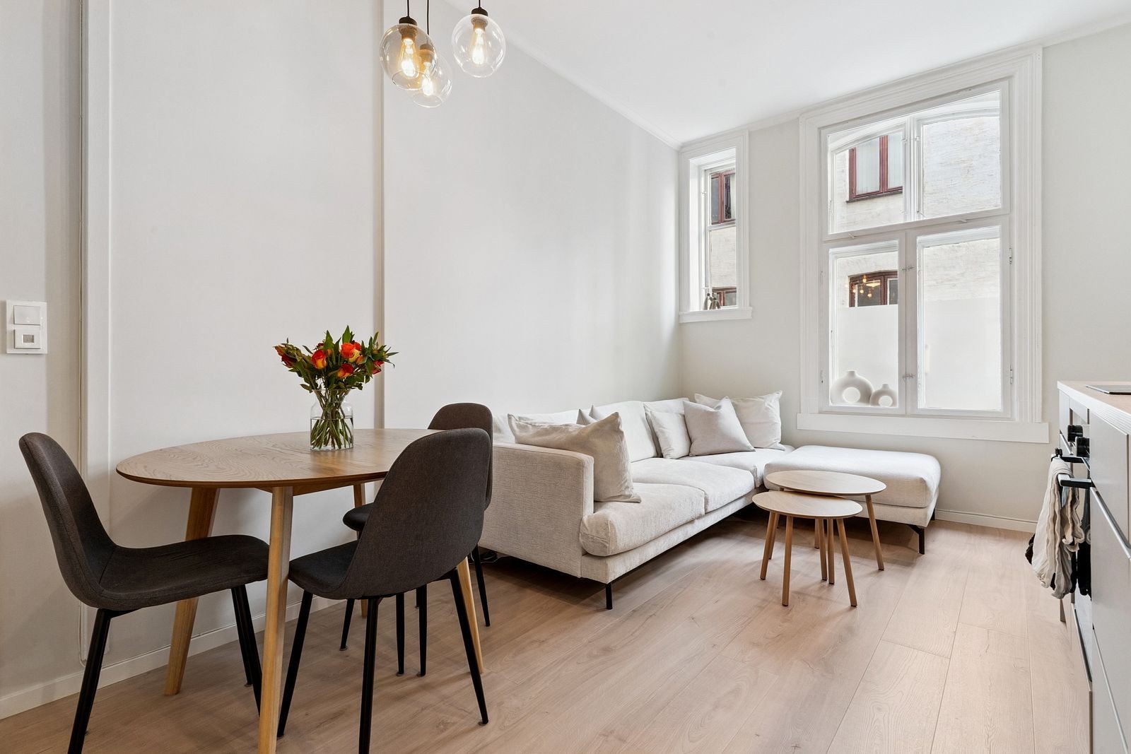 Åpen stue/kjøkken løsning med sofa og spisegruppe. Kjøkkenet har moderne innredning og god skapplass Galleribilde