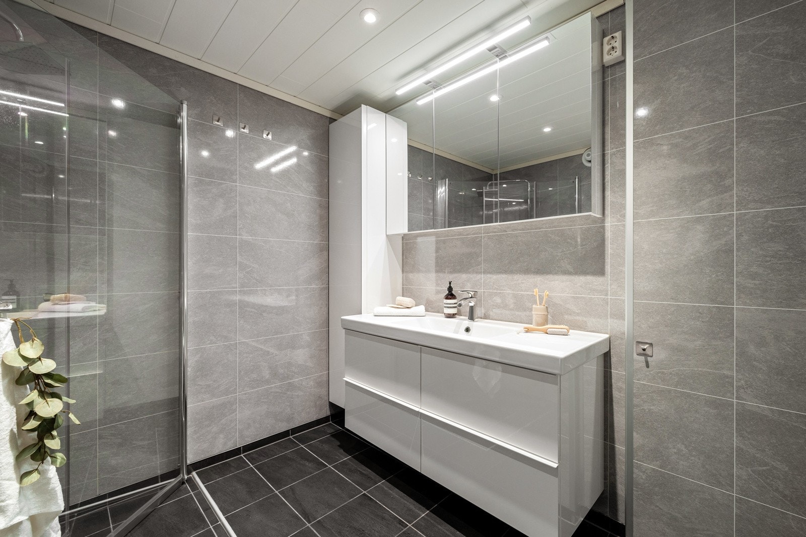 Dusjløsning med innfelbare dører i herdet glass samt dusjgarnityr med takdusj og hånddusj | Det er lagt opplegg for vaskemaskin på badet Galleribilde