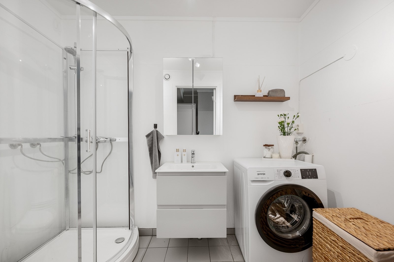 Tidløst og funksjonelt bad med gulvmontert toalett, dusjkabinett, baderomsinnredning og opplegg for vaskemaskin. Galleribilde