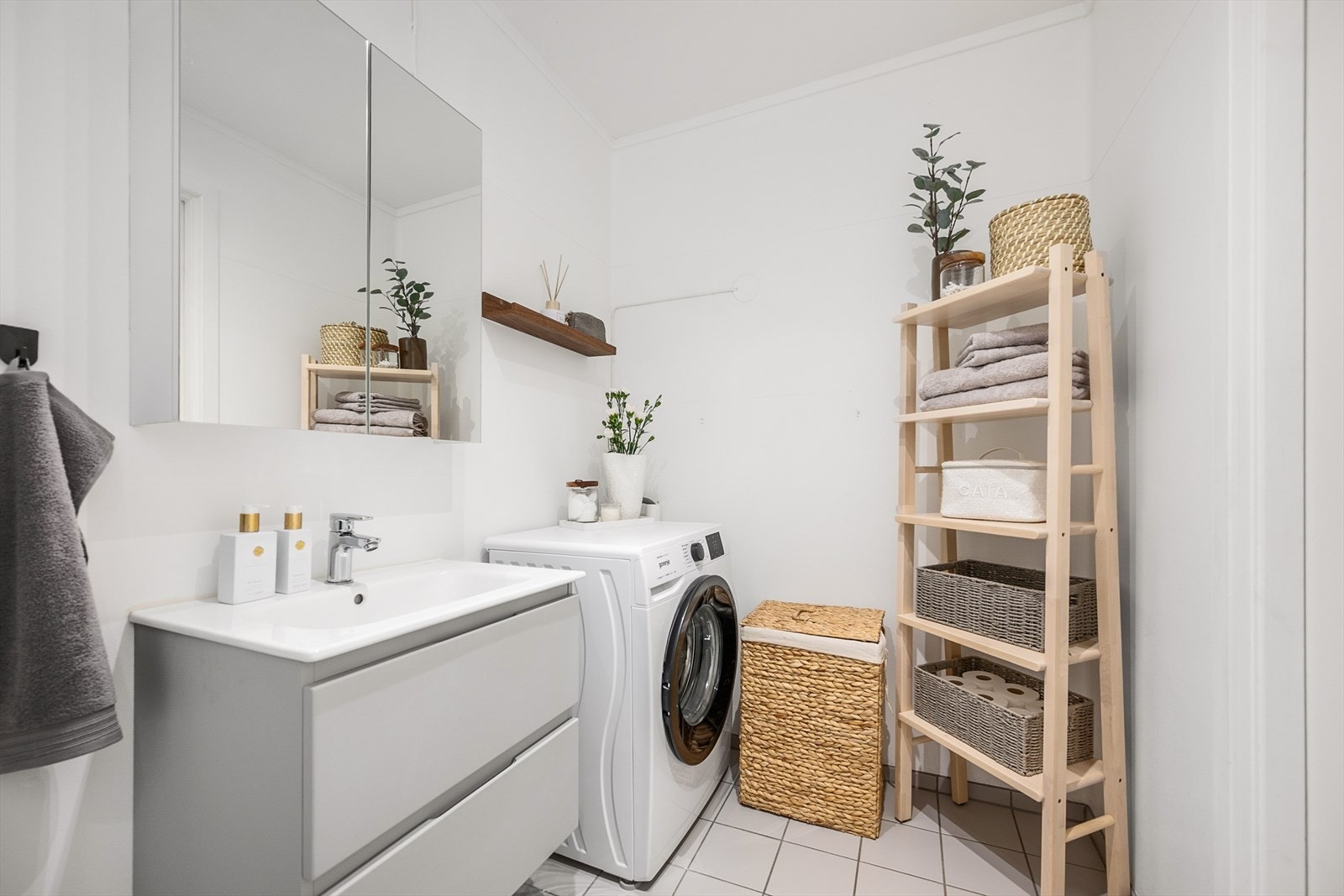 Her inne er det gulvmontert toalett, dusjdører i herdet glass, baderomsinnredning og opplegg for vaskemaskin. Galleribilde