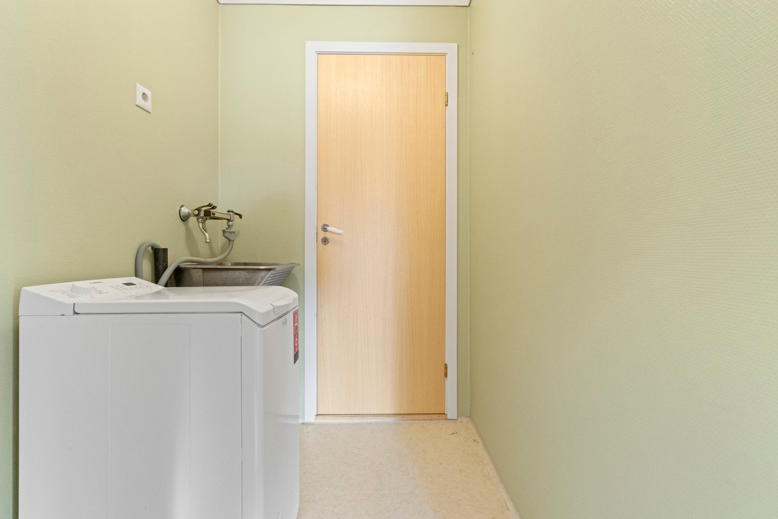 Eget vaskerom med belegg, vegger med malt glasfiberstrie og himling med folierte trefiberplater. Vegghengt skyllekar med opplegg for vaskemaskin. Galleribilde