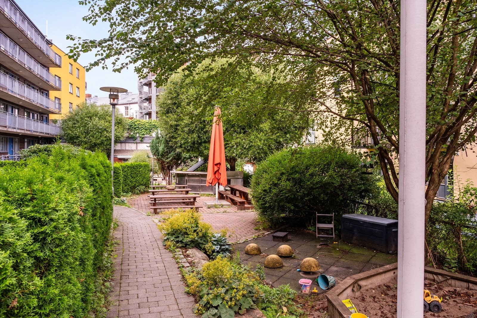 Felles gårdsrom er pent opparbeidet med gangstier, lekeapparater og hyggelig beplanting. Galleribilde