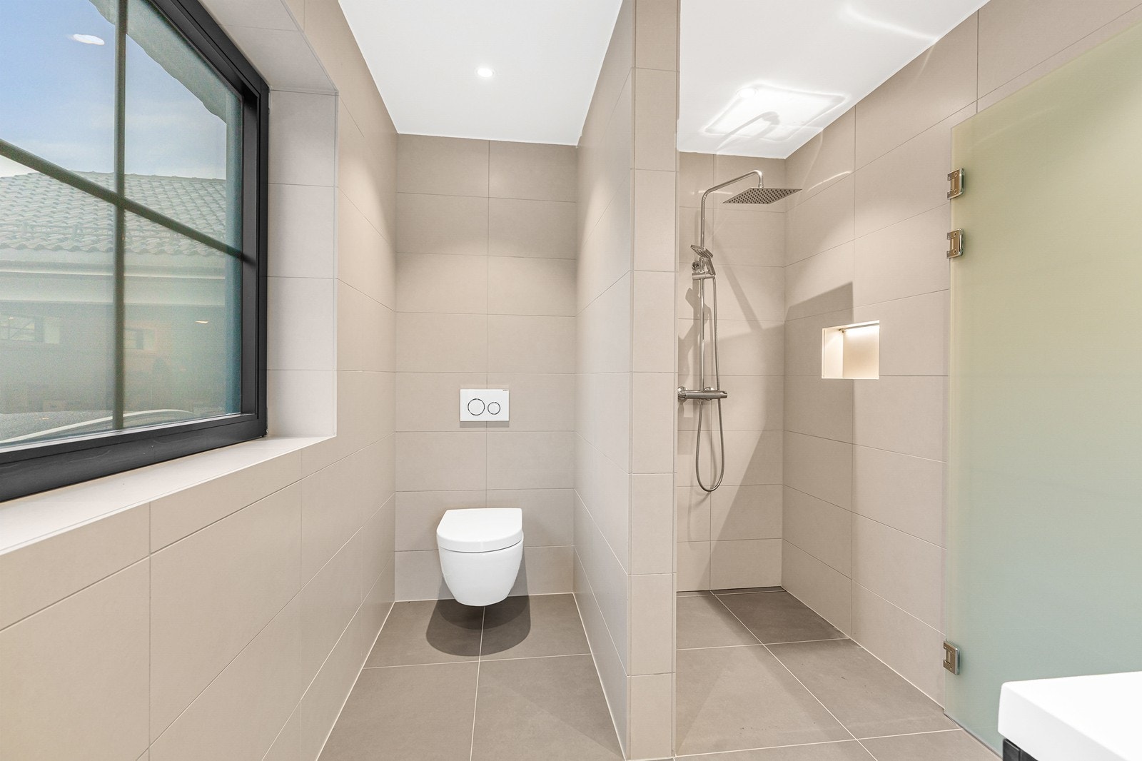 Badene er helfliset og er innredet med baderomsinnredning med servant, vegghengt toalett og dusj. Galleribilde