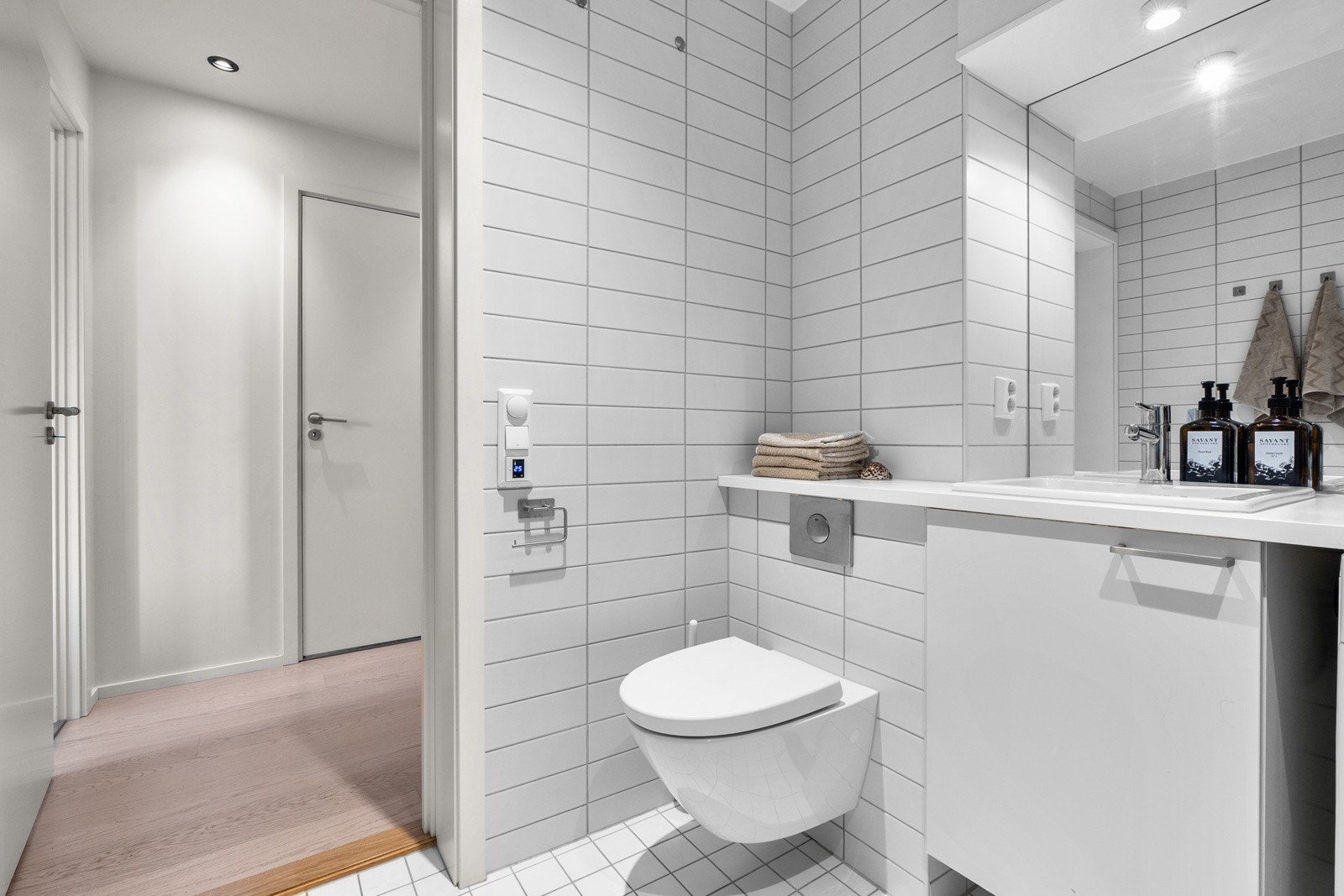 .Baderommet har vegghengt servantinnredning, ovenpåliggende servant, speilskap med overlys og stikkontakt over servant. Det er videre dusjhjørne med hånddusj og regndusj, vegghengt toalett og opplegg for vaskemaskin. Galleribilde